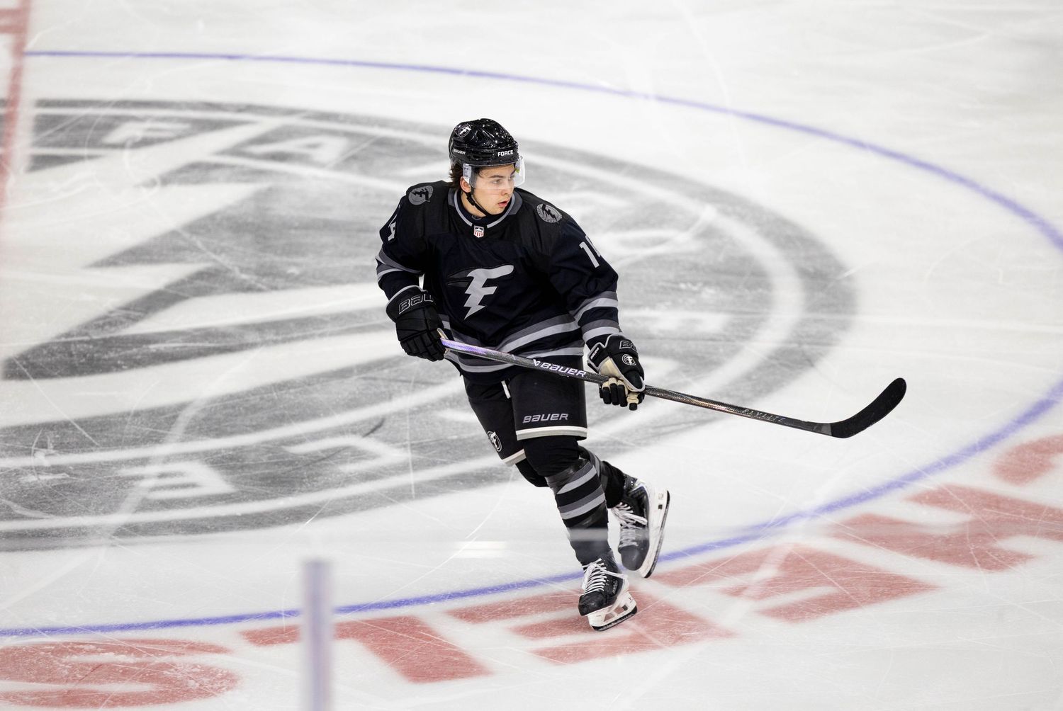 Hockey player in black uniform skating on ice rink during game.