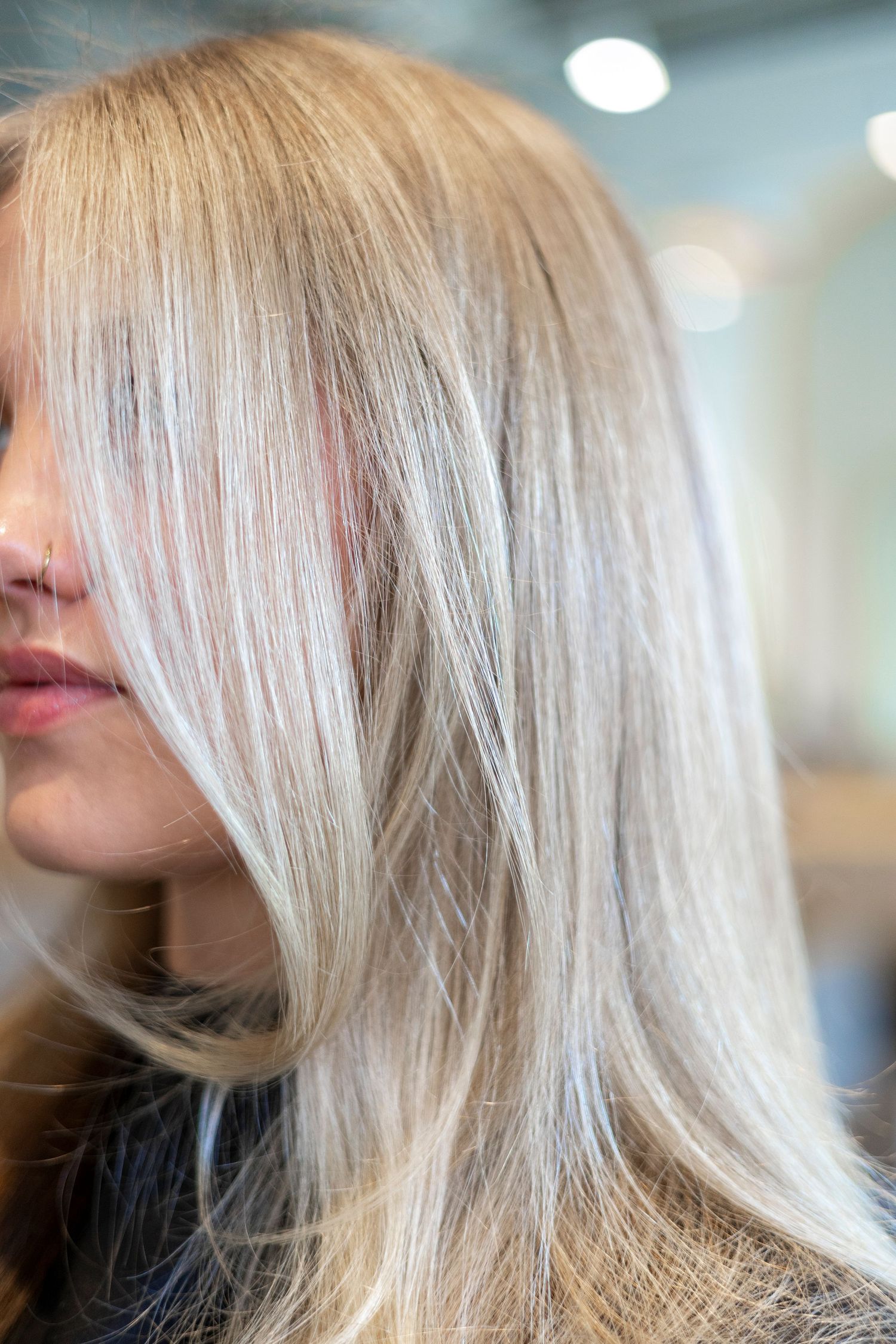 Woman with sleek, straight platinum blonde hair styled at a professional hair salon.