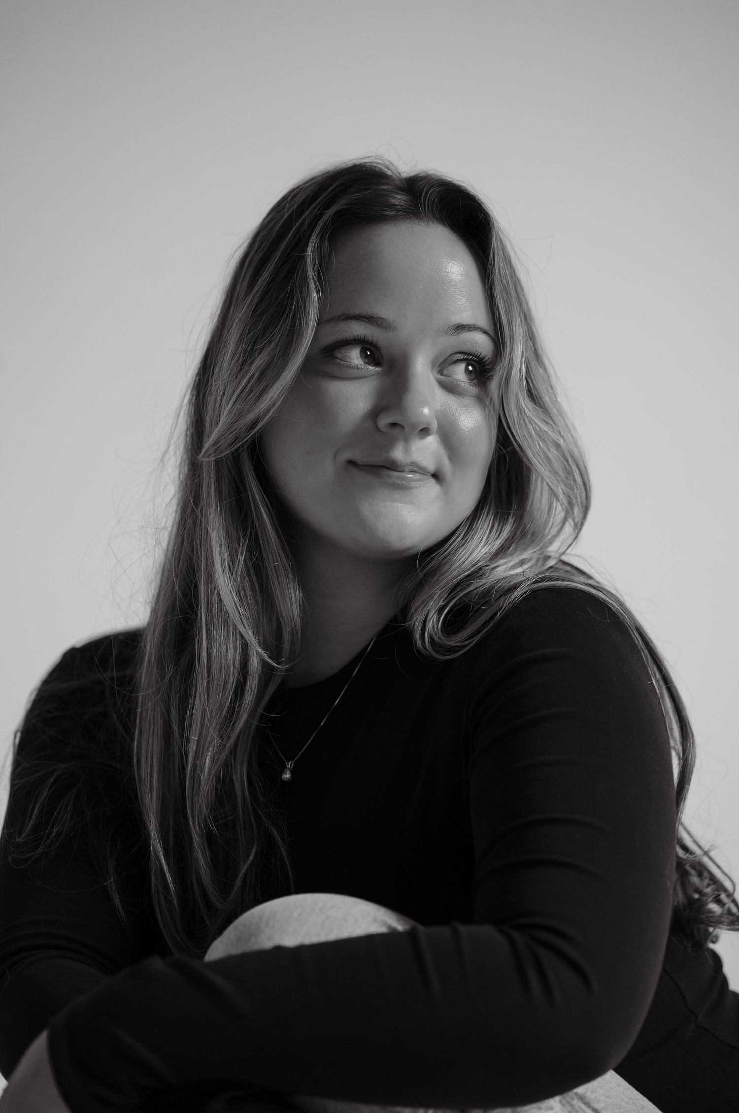 Black and white portrait of woman in black top looking up pensively.