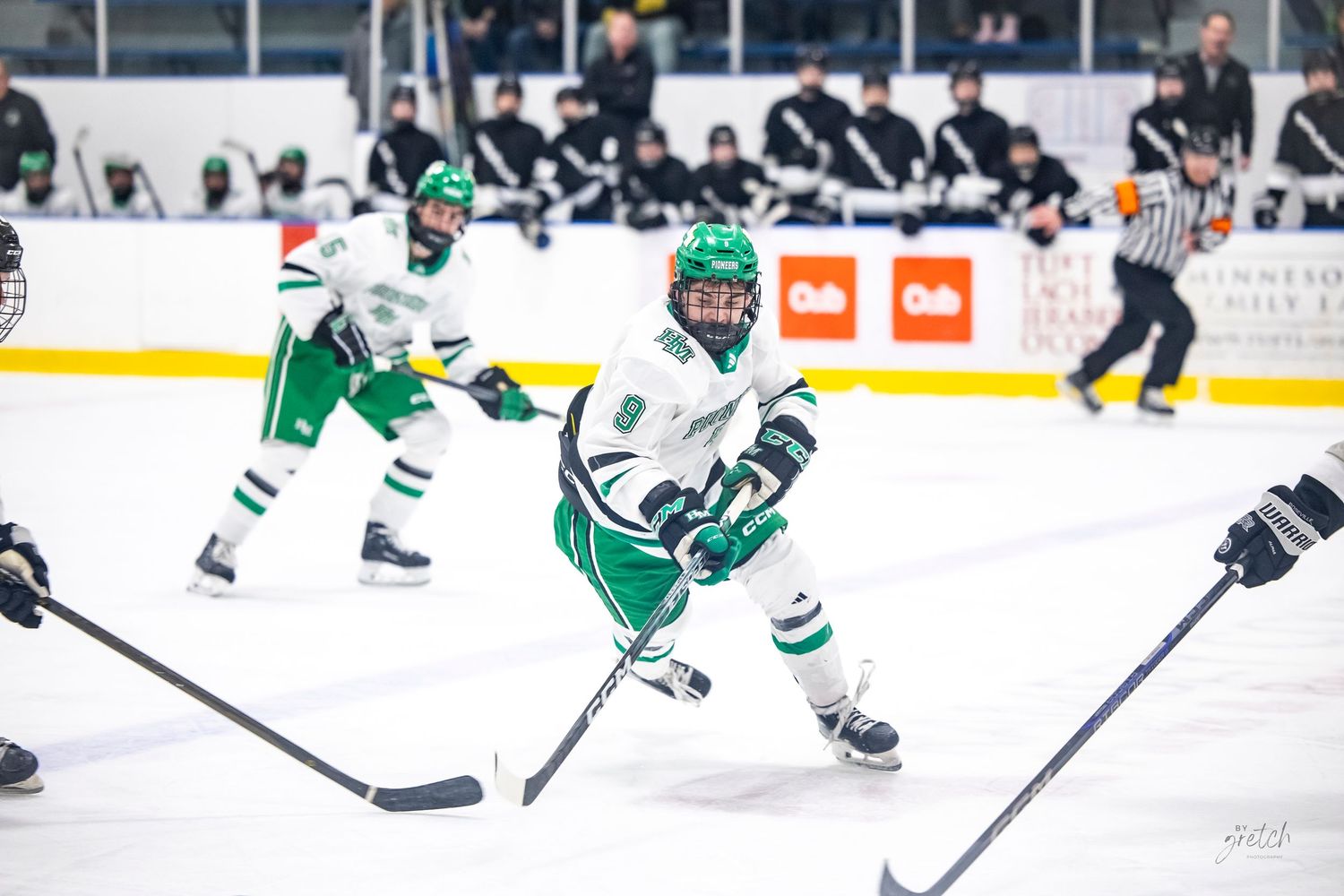 Hill-Murray Pioneers hockey player skating with the puck during a competitive ice hockey game.