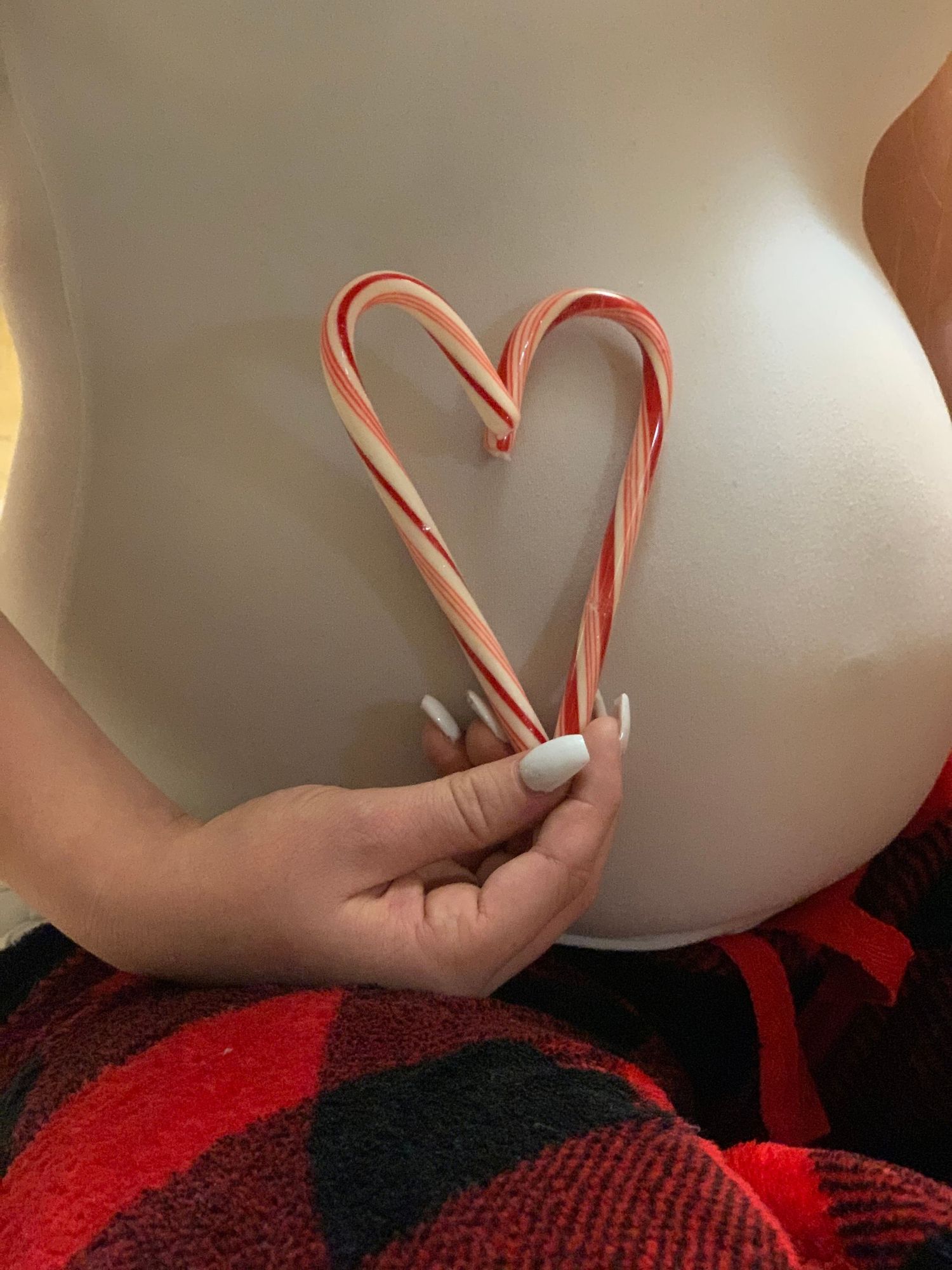 Maternity portrait with candy canes forming a heart over baby bump