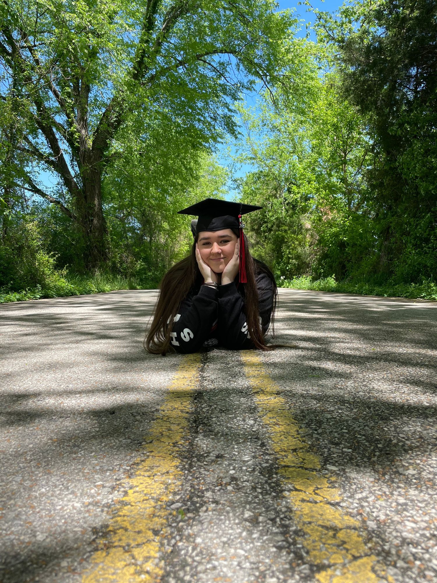 Senior graduate portrait in cap and gown on a country road