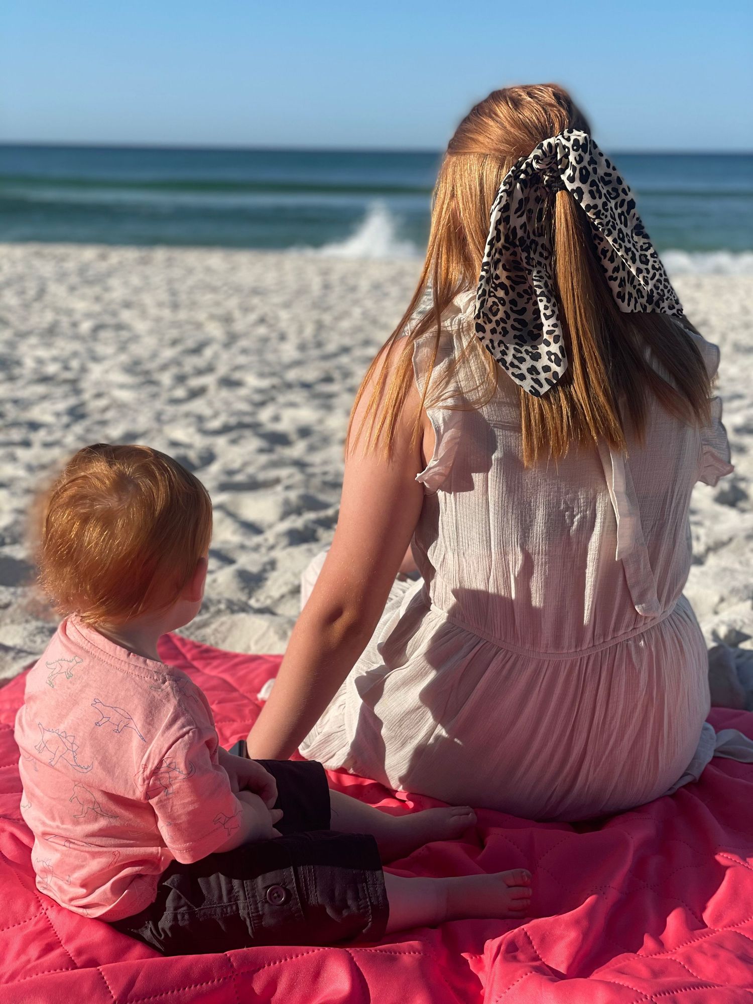 Mother and child sitting together on the beach overlooking the ocean