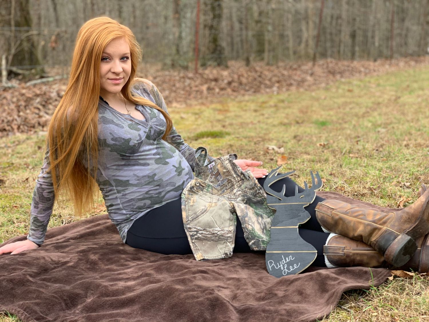 Maternity portrait with baby items in a rustic outdoor setting