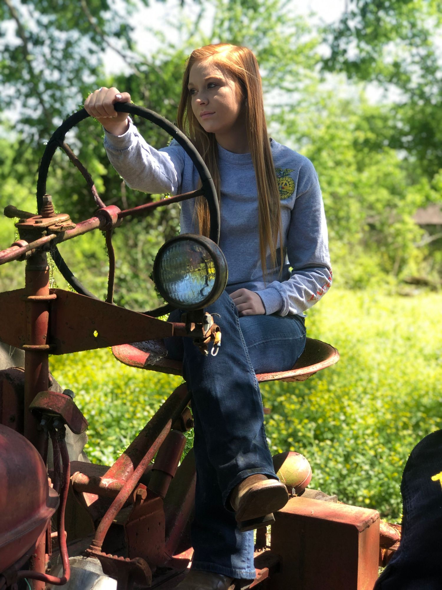 Outdoor portrait of a young woman sitting on a vintage tractor