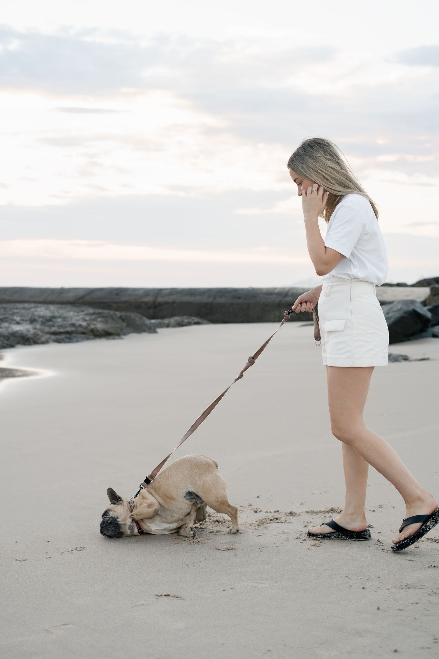 Woman walking her dog on the beach during a natural pet photography session on the Gold Coast