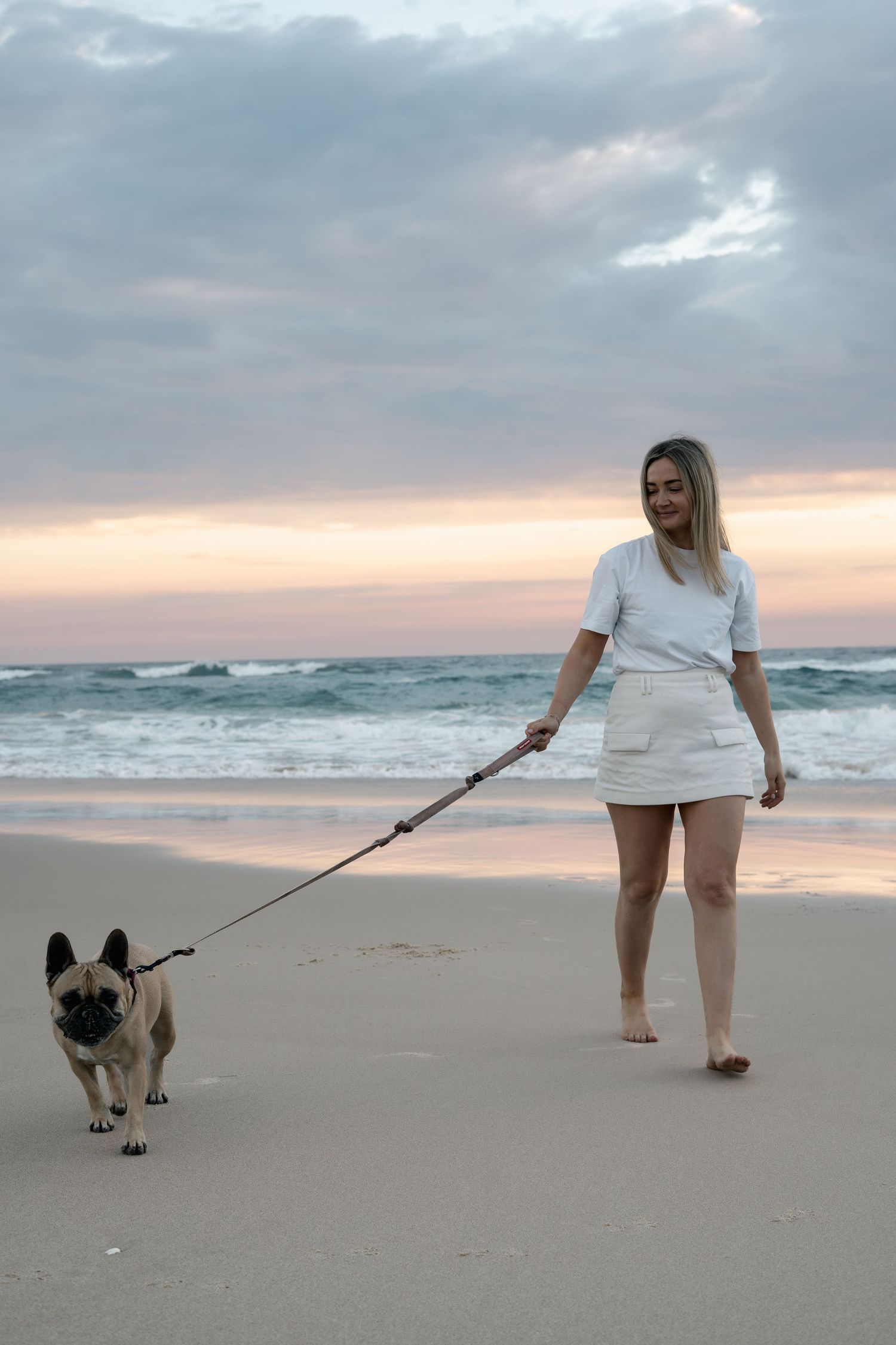 Woman walking her dog on the beach during a natural pet photography session on the Gold Coast