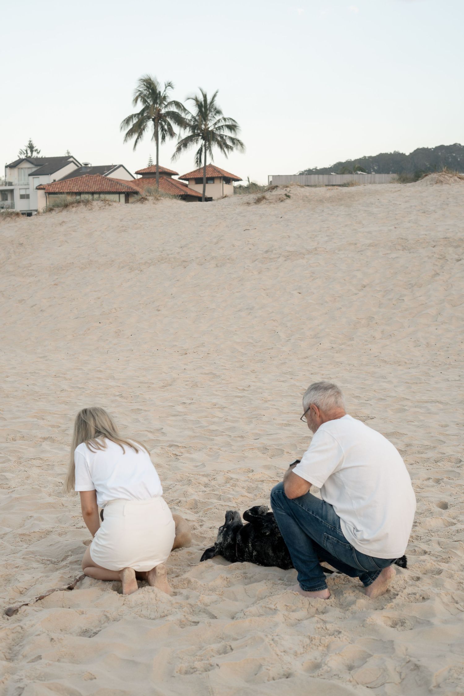 Father and daughter with their dogs on the beach during a natural pet photography session on the Gold Coast