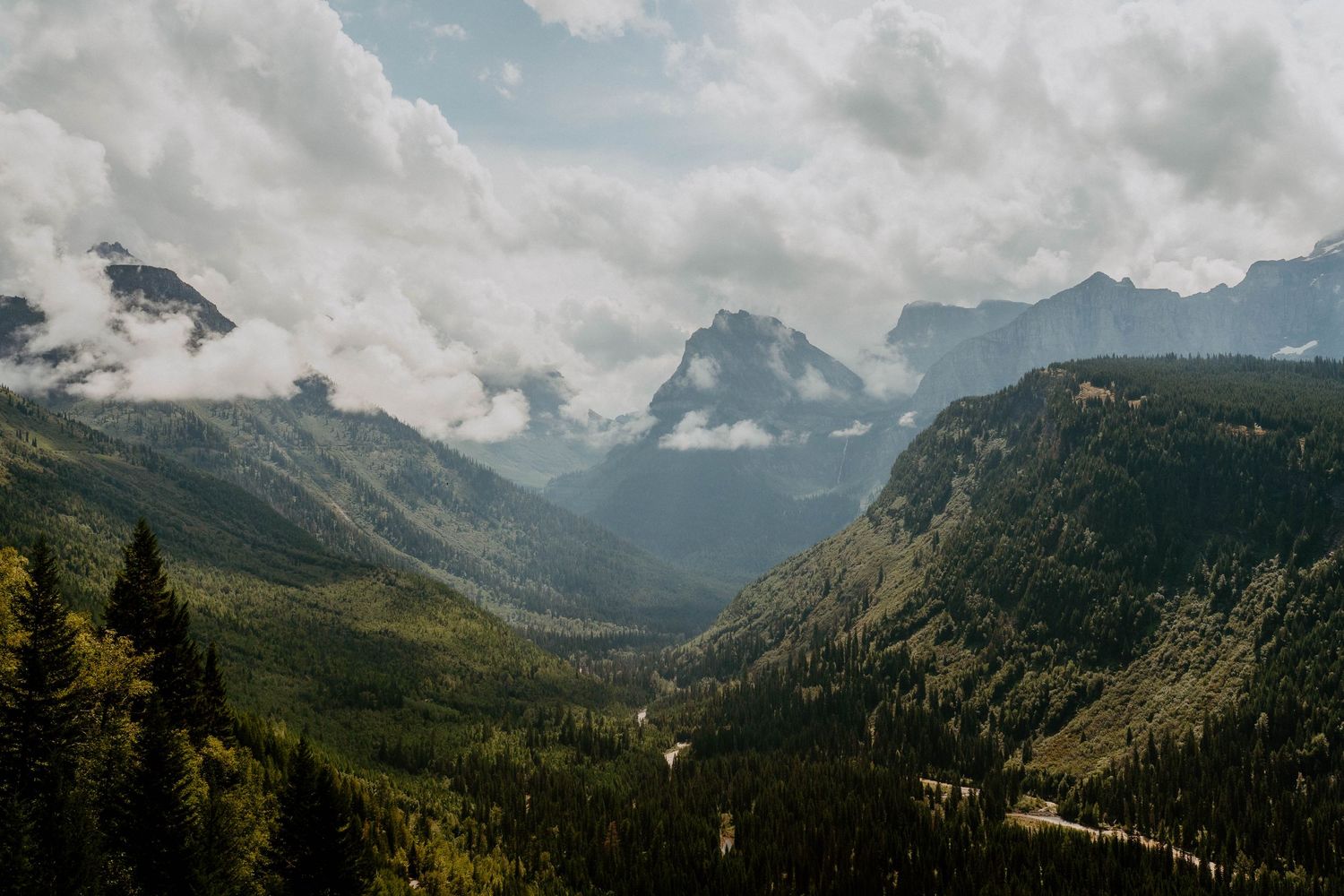 Dramatic mountain landscape with misty peaks and valleys under cloudy skies.