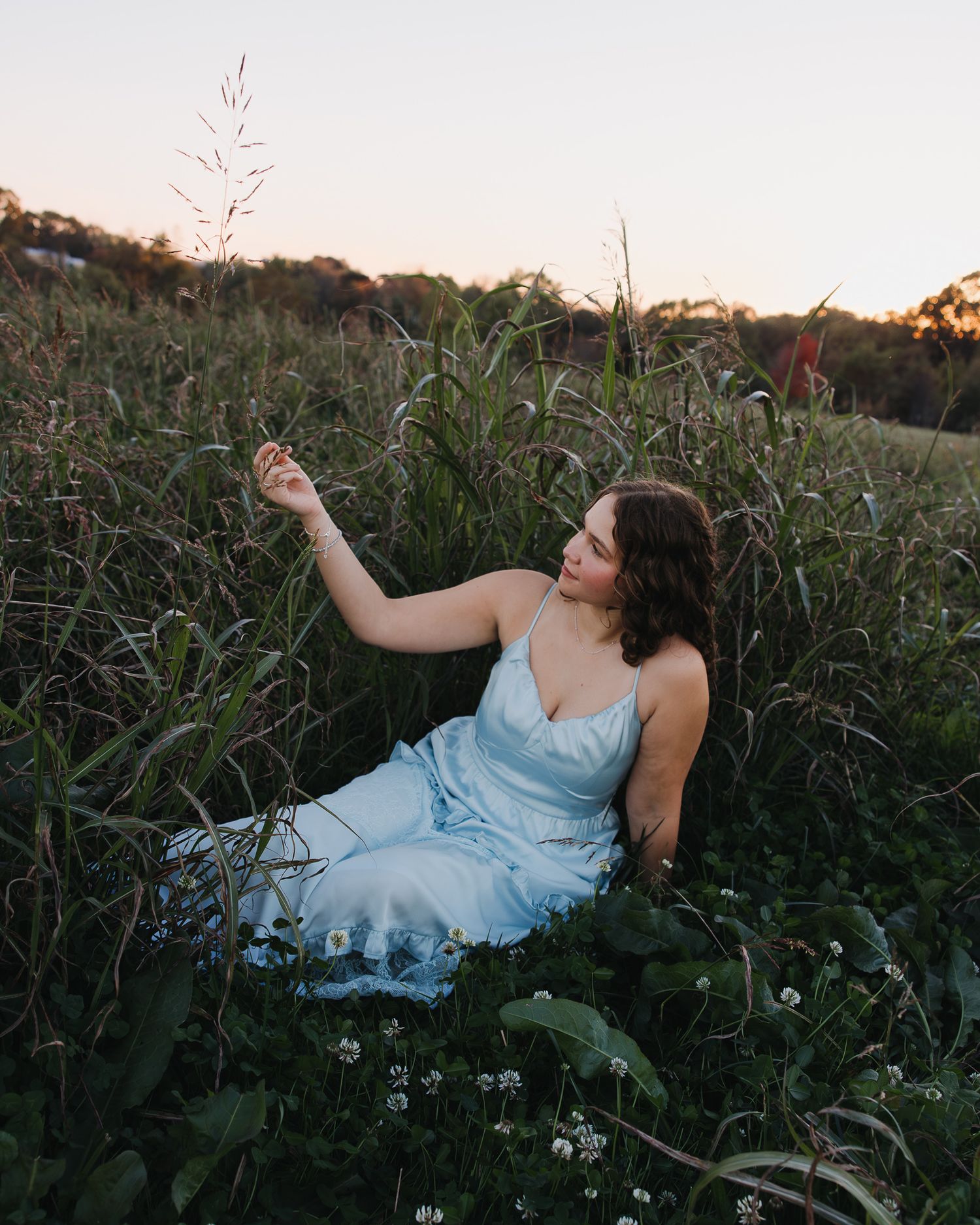 Woman in blue dress reclines in a wildflower field during golden hour.