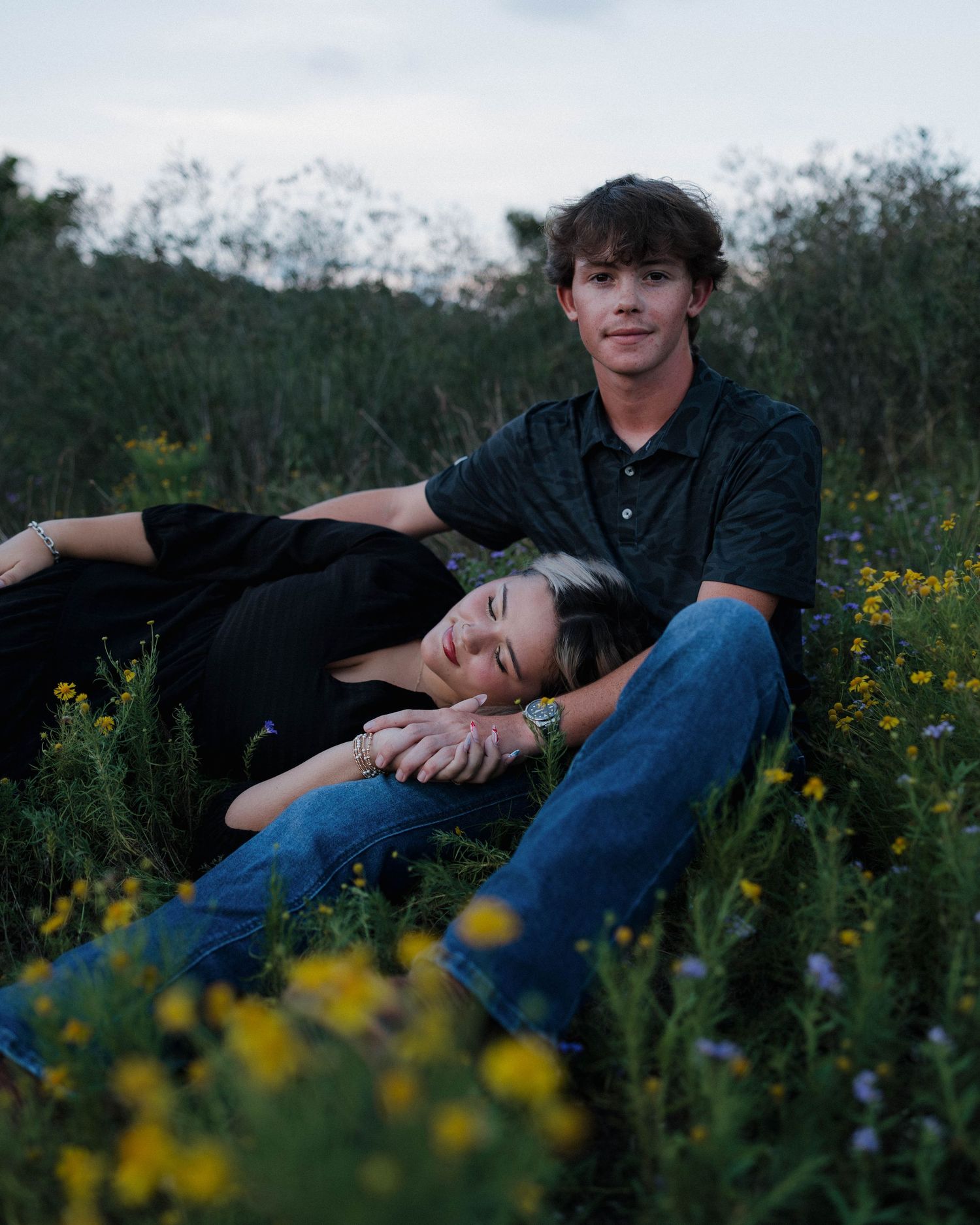 Couple relaxing in a field of wildflowers during a romantic outdoor photo session.