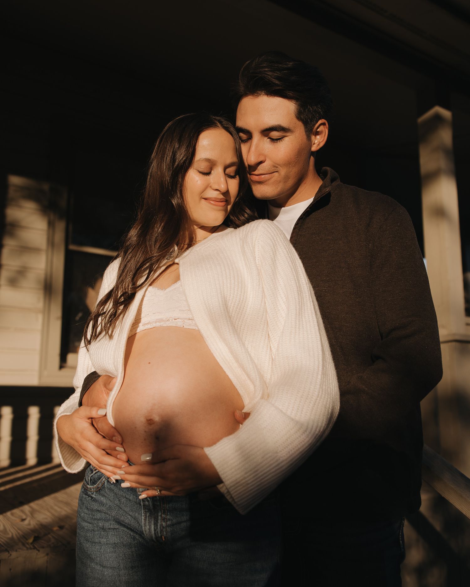 Moody indoor maternity photos with dramatic lighting showing tender pregnancy moments.