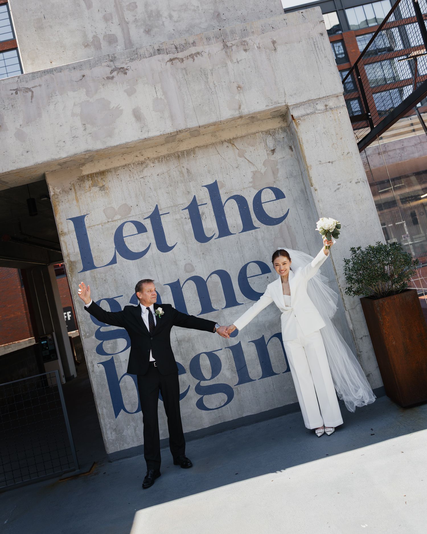 Bride and groom celebrate in front of 'Let the games begin' mural in Downtown Nashville Tennessee.