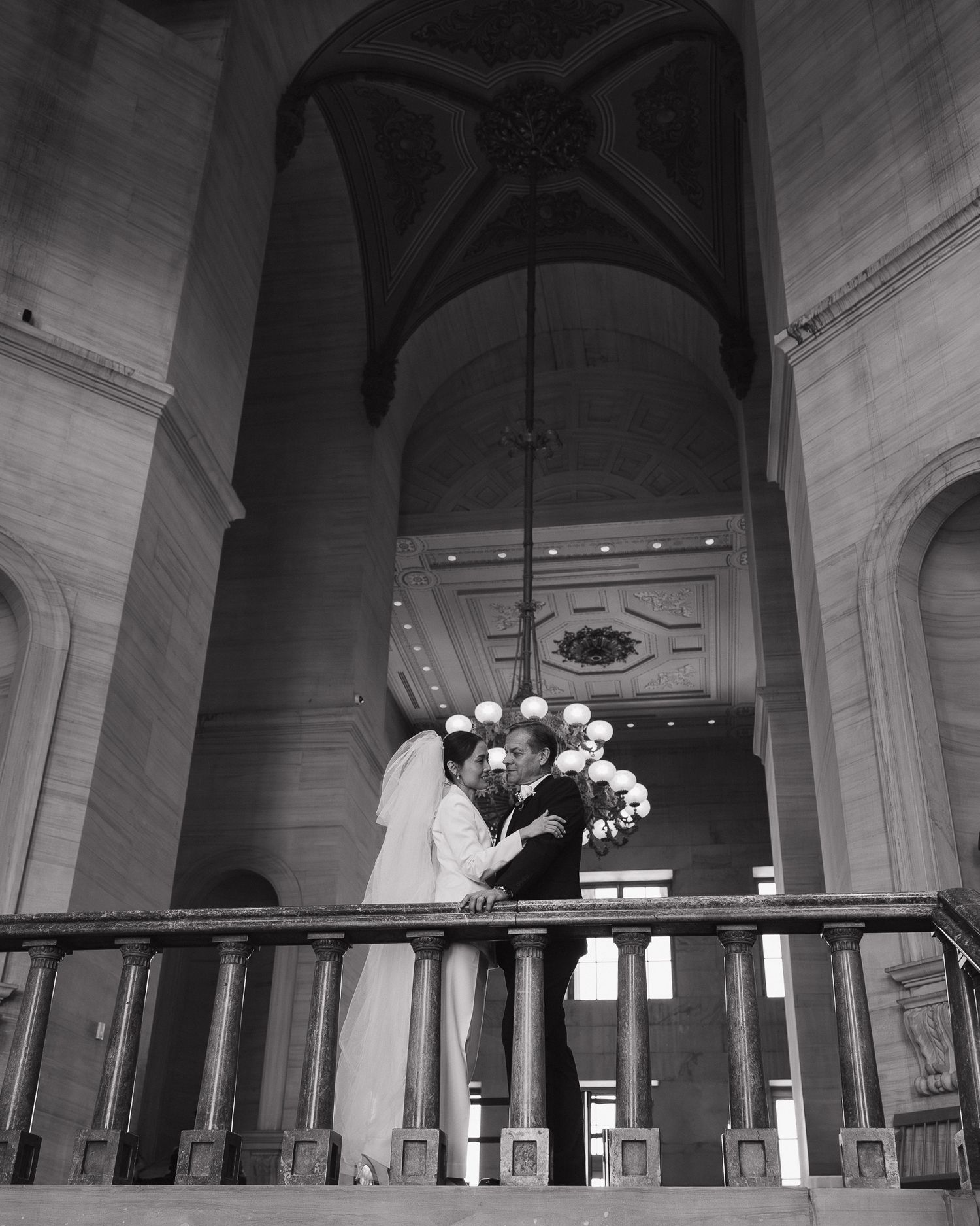 Black and white photo of a bride and groom kissing on a balcony inside an elegant Nashville Tennessee State Capitol Building.