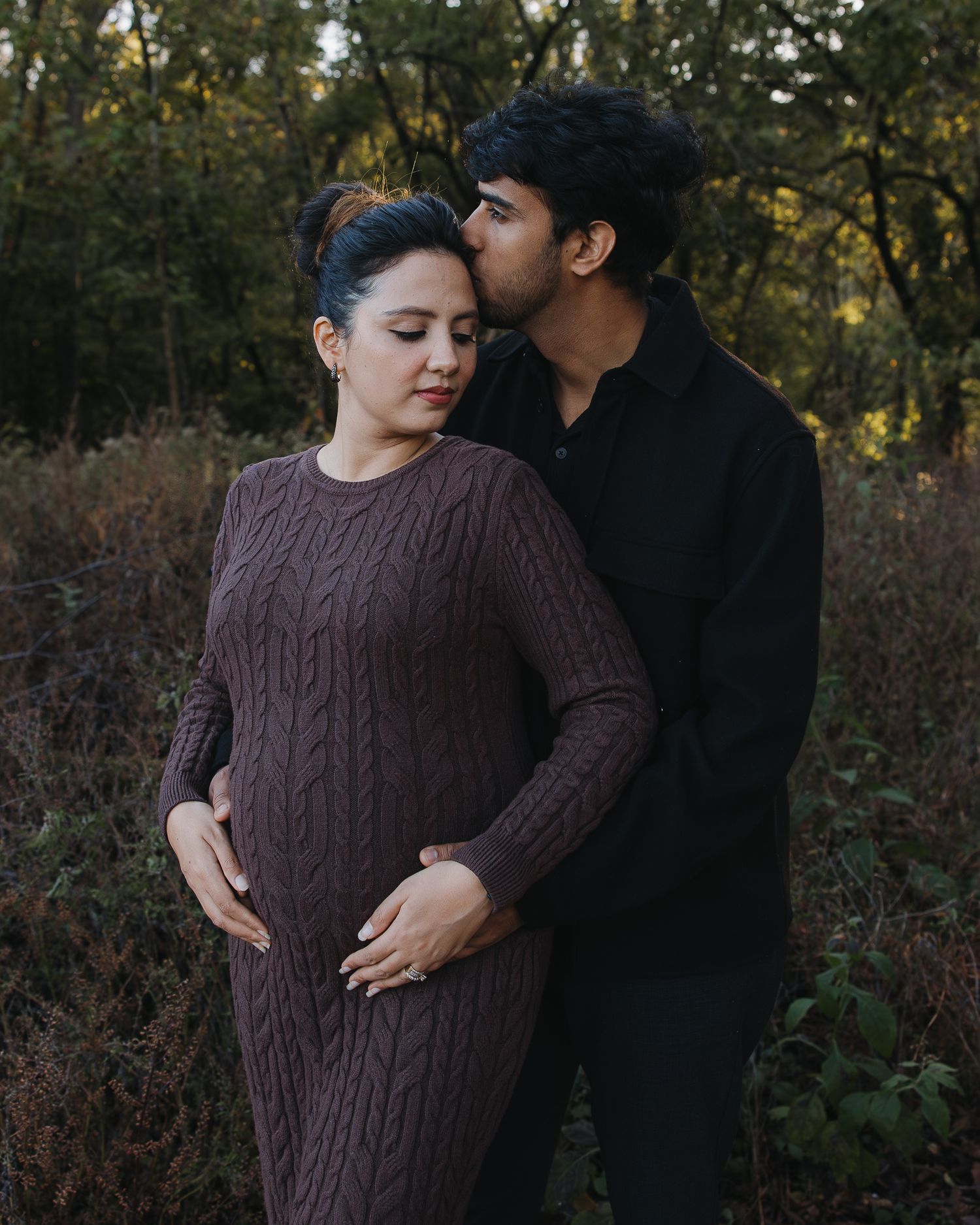Intimate moment between couple wearing cozy sweaters in an outdoor fall setting.