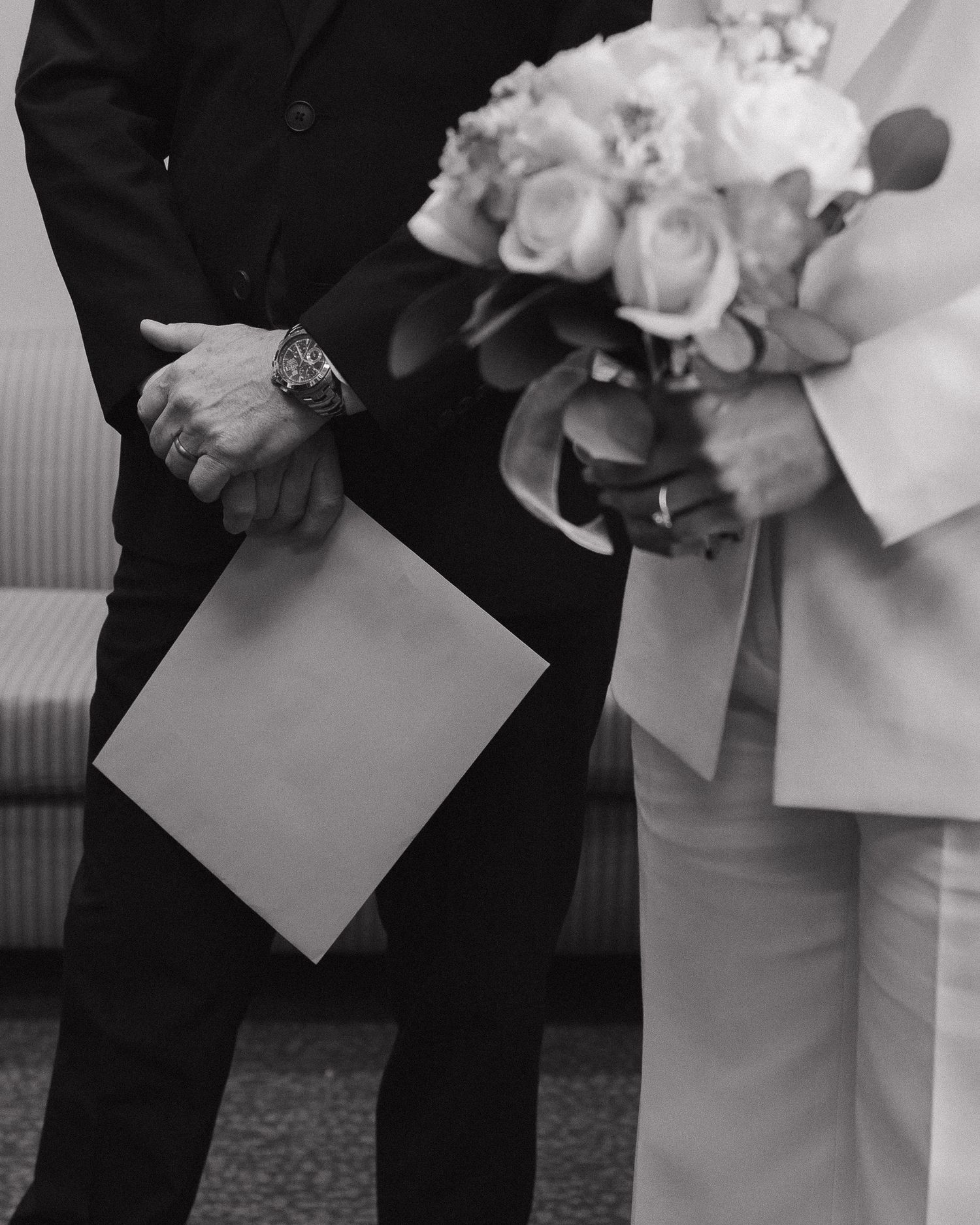Black and white photo of a groom holding vows and a bride with a rose bouquet at a courthouse wedding ceremony in Nashville.