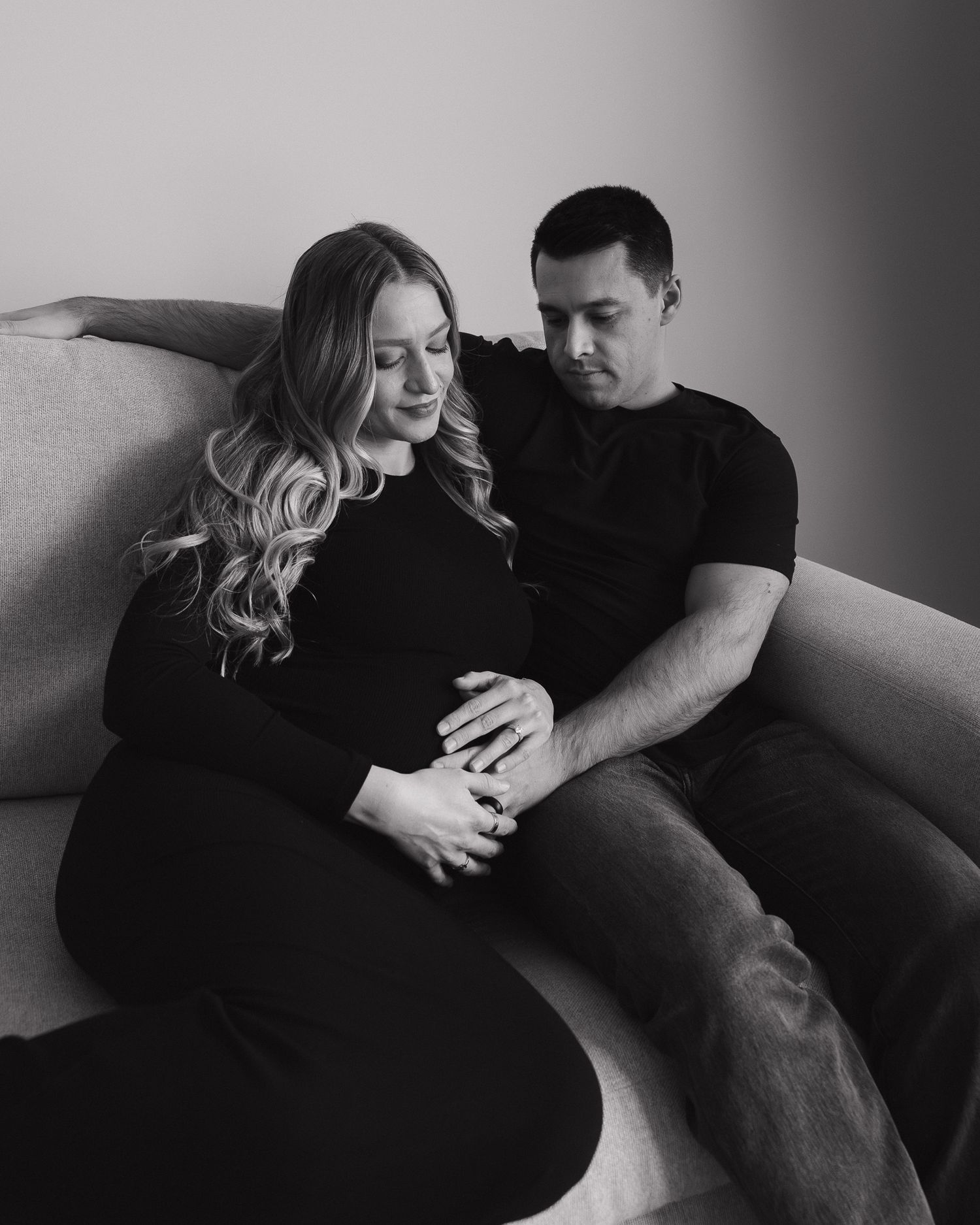 Intimate black and white photo series showing a couple cuddling and embracing on a couch in candid moments.