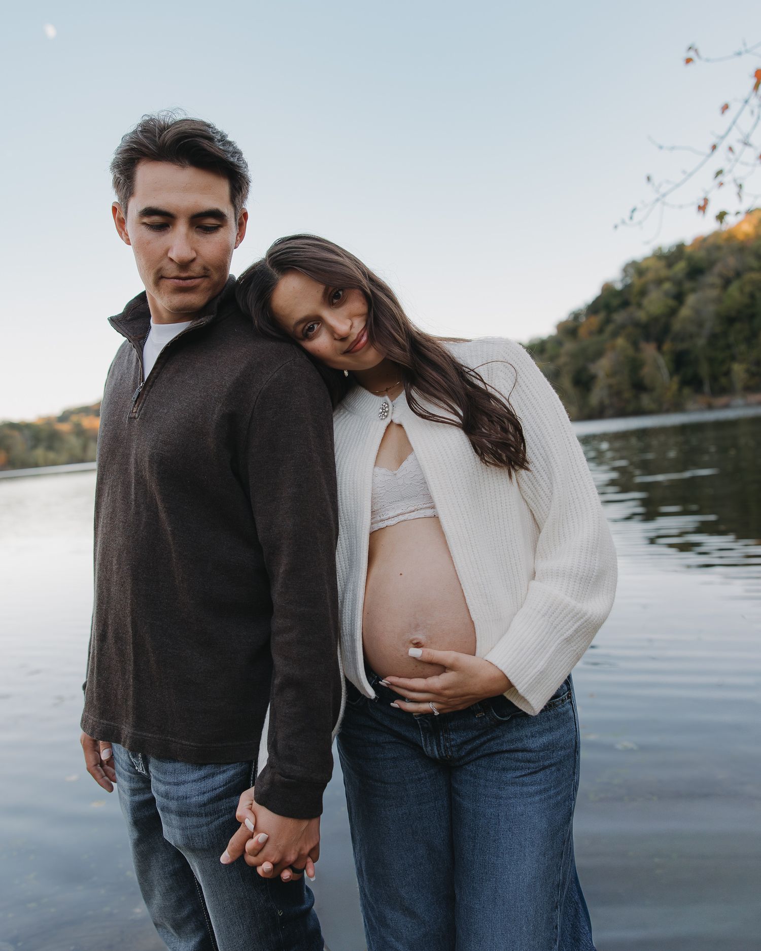 Lakeside maternity photos at sunset capturing intimate moments between expecting parents.