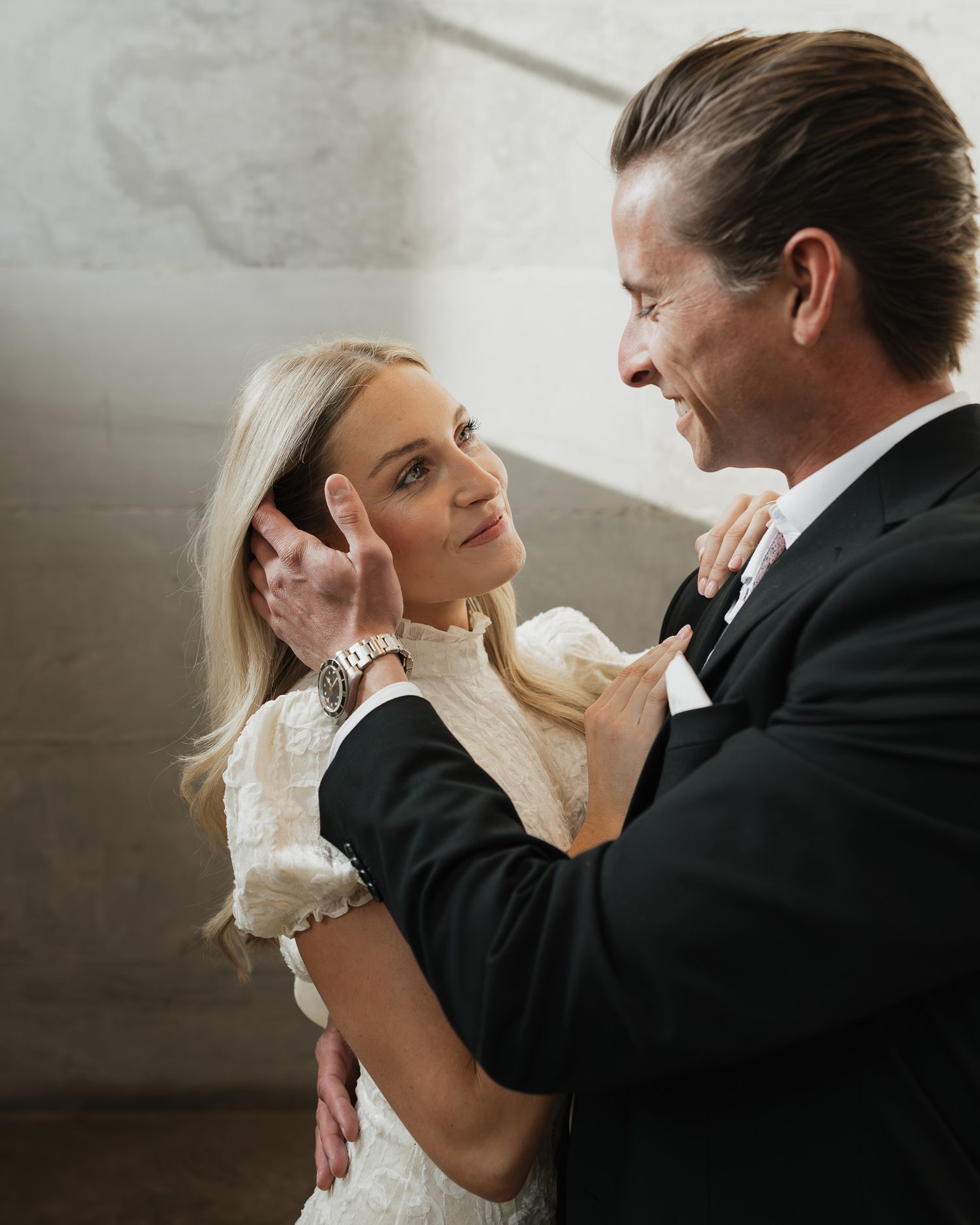 A couple shares an intimate moment dancing together, with the woman in a white dress and man in a black suit.