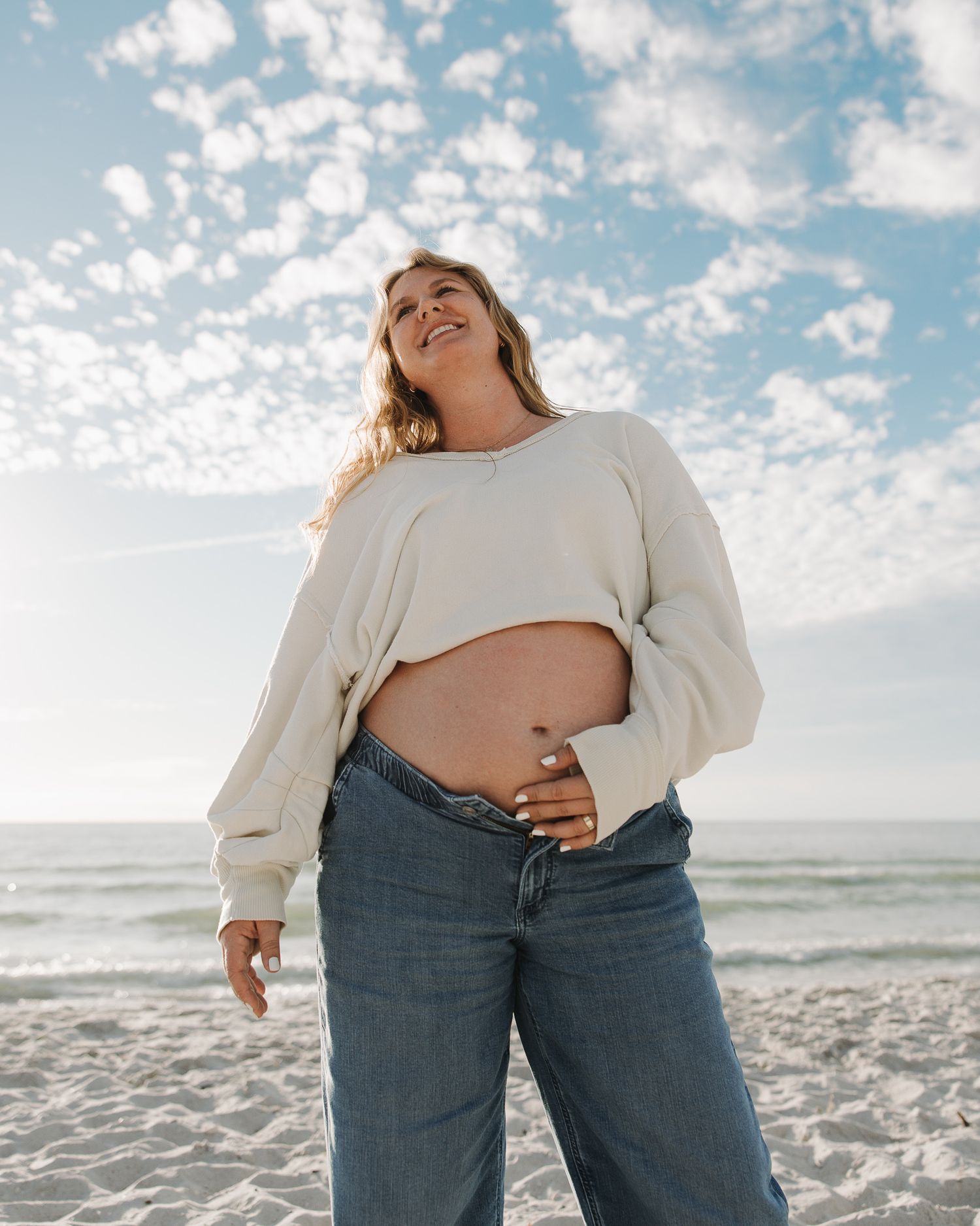 Beachside maternity photography with bright blue skies and white sand.