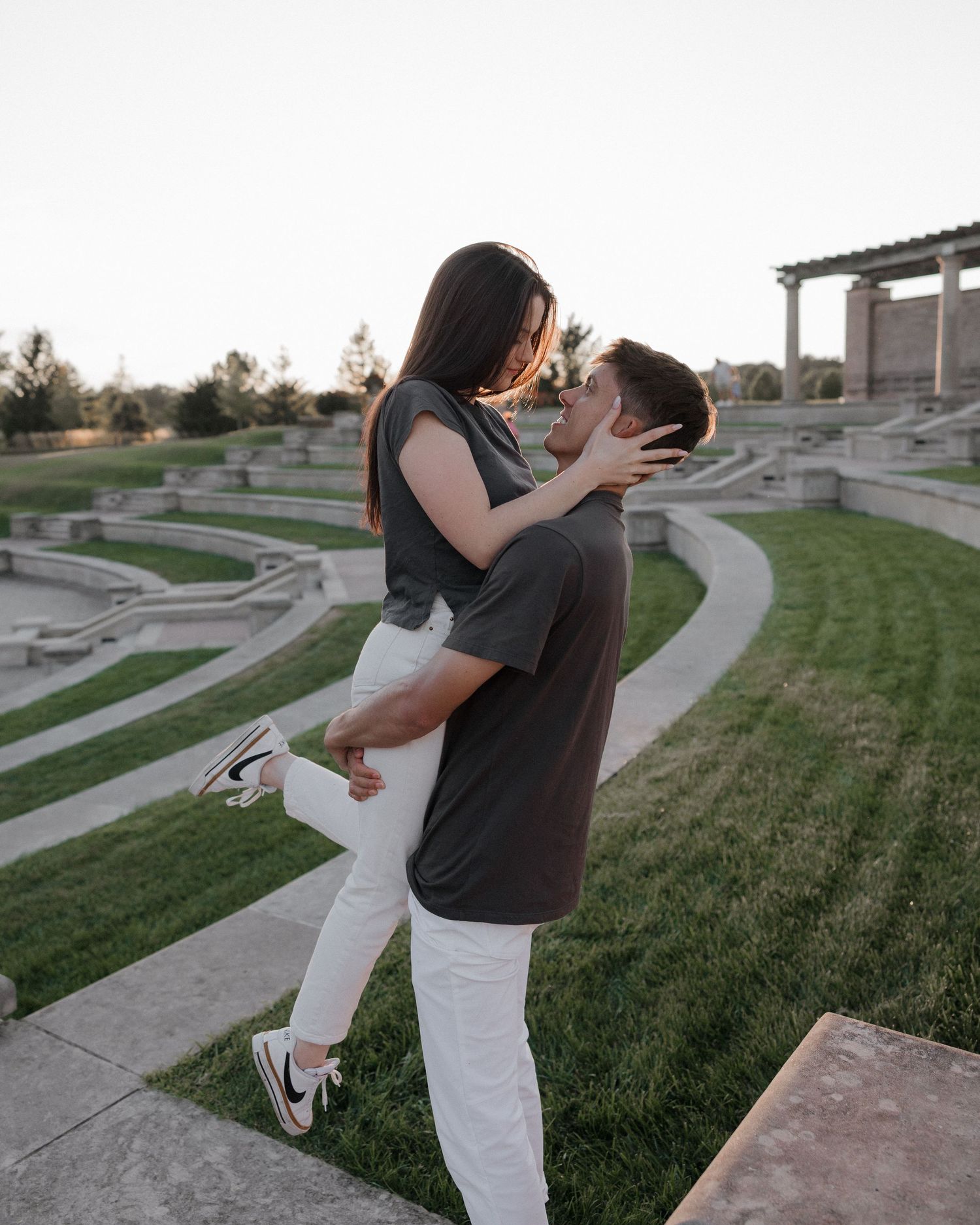 Couple posing near stone amphitheater steps at sunset.