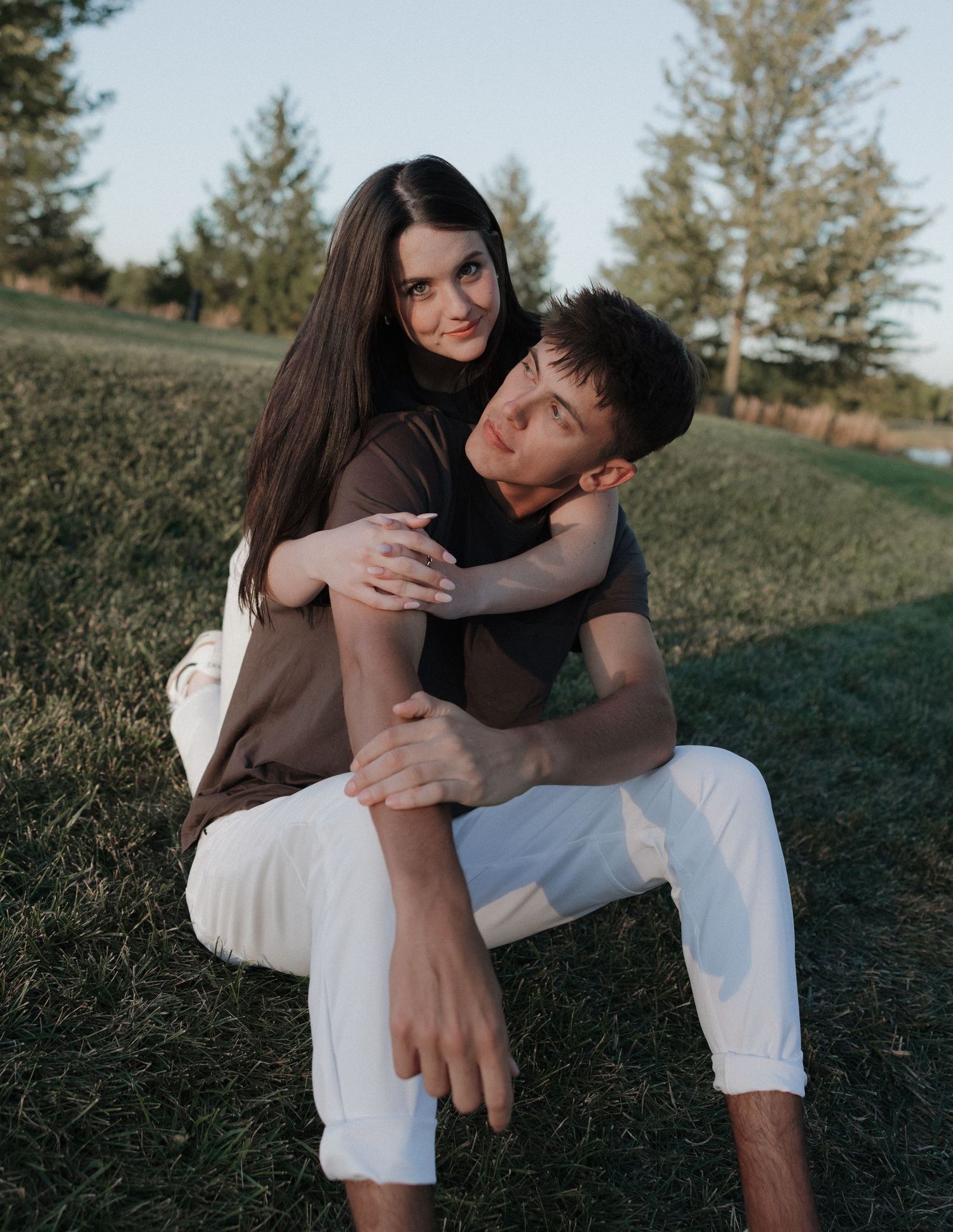 Intimate outdoor portrait session showing couple embracing on grass.