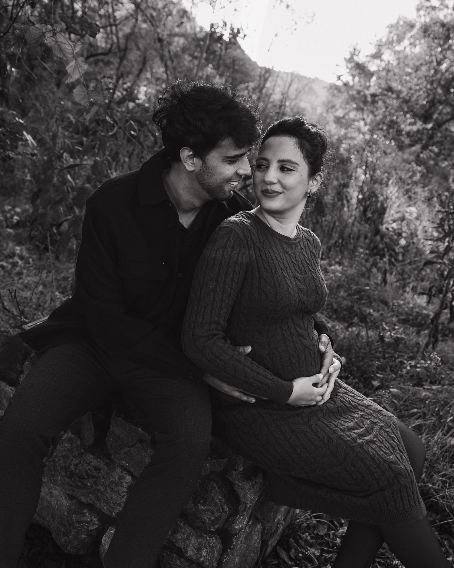 Black and white portrait of couple embracing in a natural wooded setting.