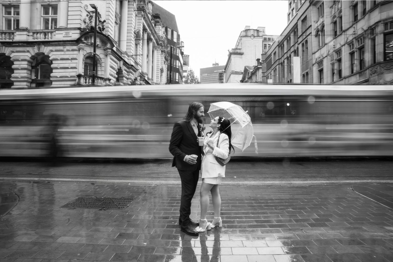 Bride and groom enjoying a coffee from Blank Street and passing tram in Manchester captured by Manchester wedding photographer.