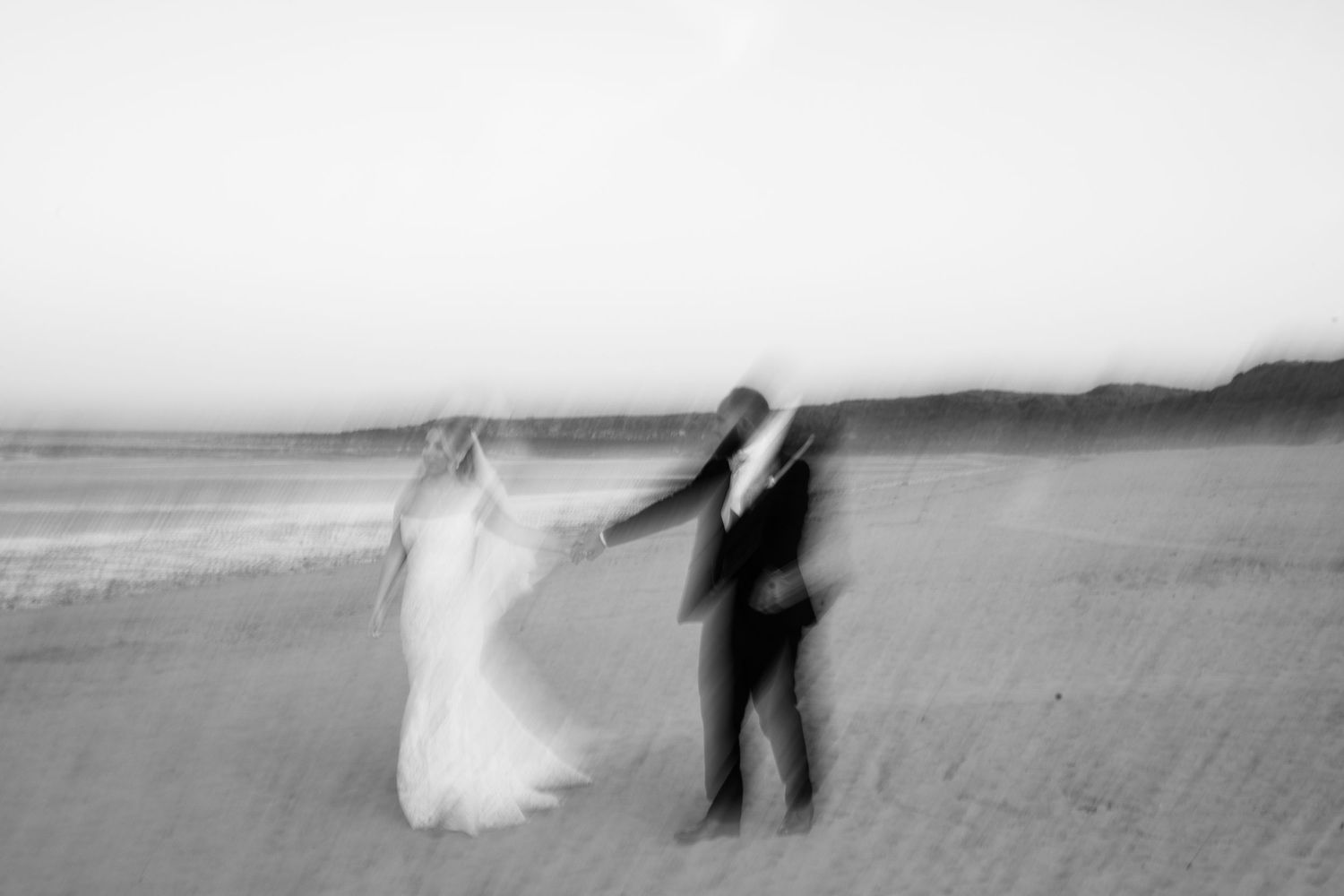 Editorial couple walks on UK beach by Manchester wedding photographer Tina Hevingham.