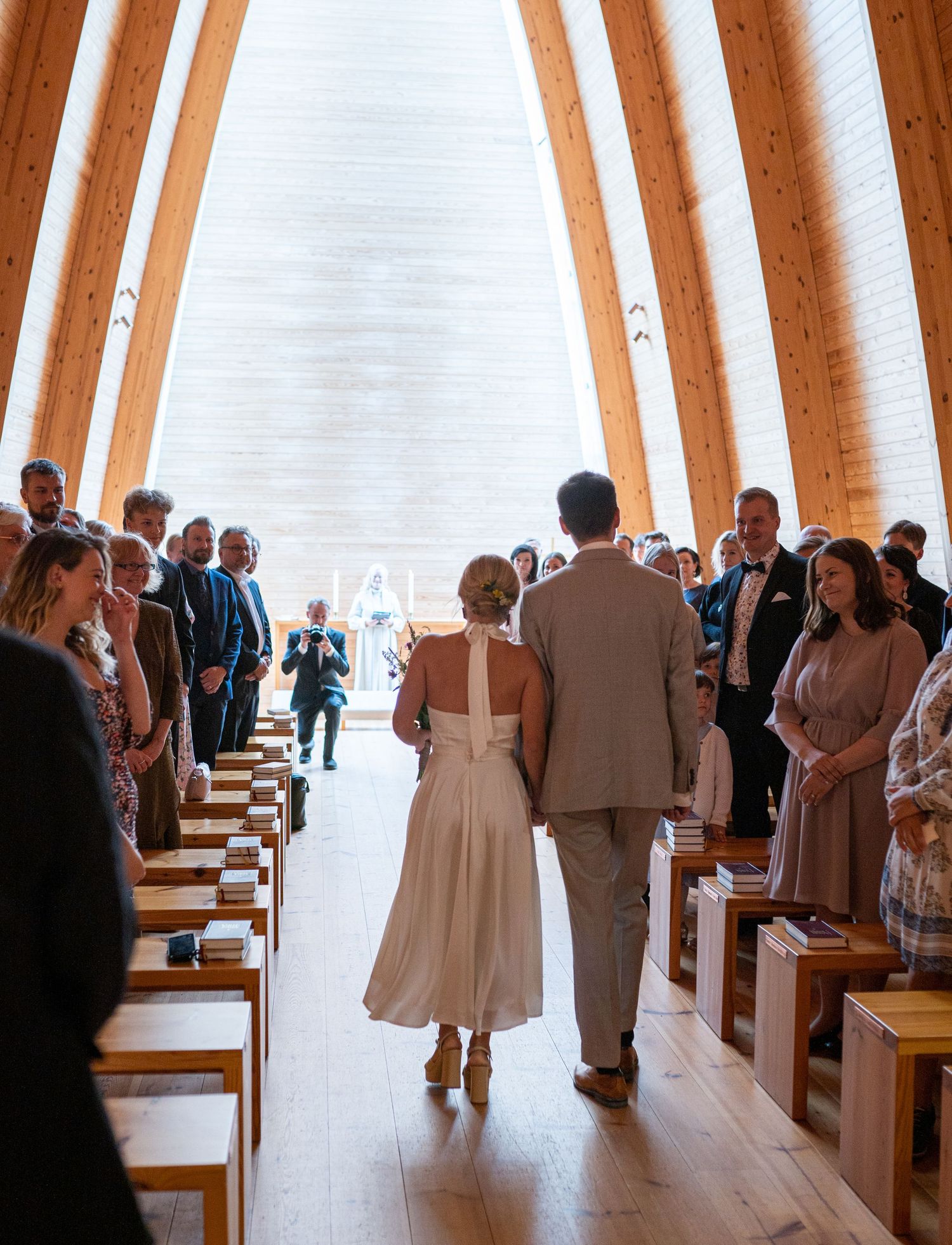 Bride and groom walk down the aisle of a stunning wooden chapel during their wedding ceremony.