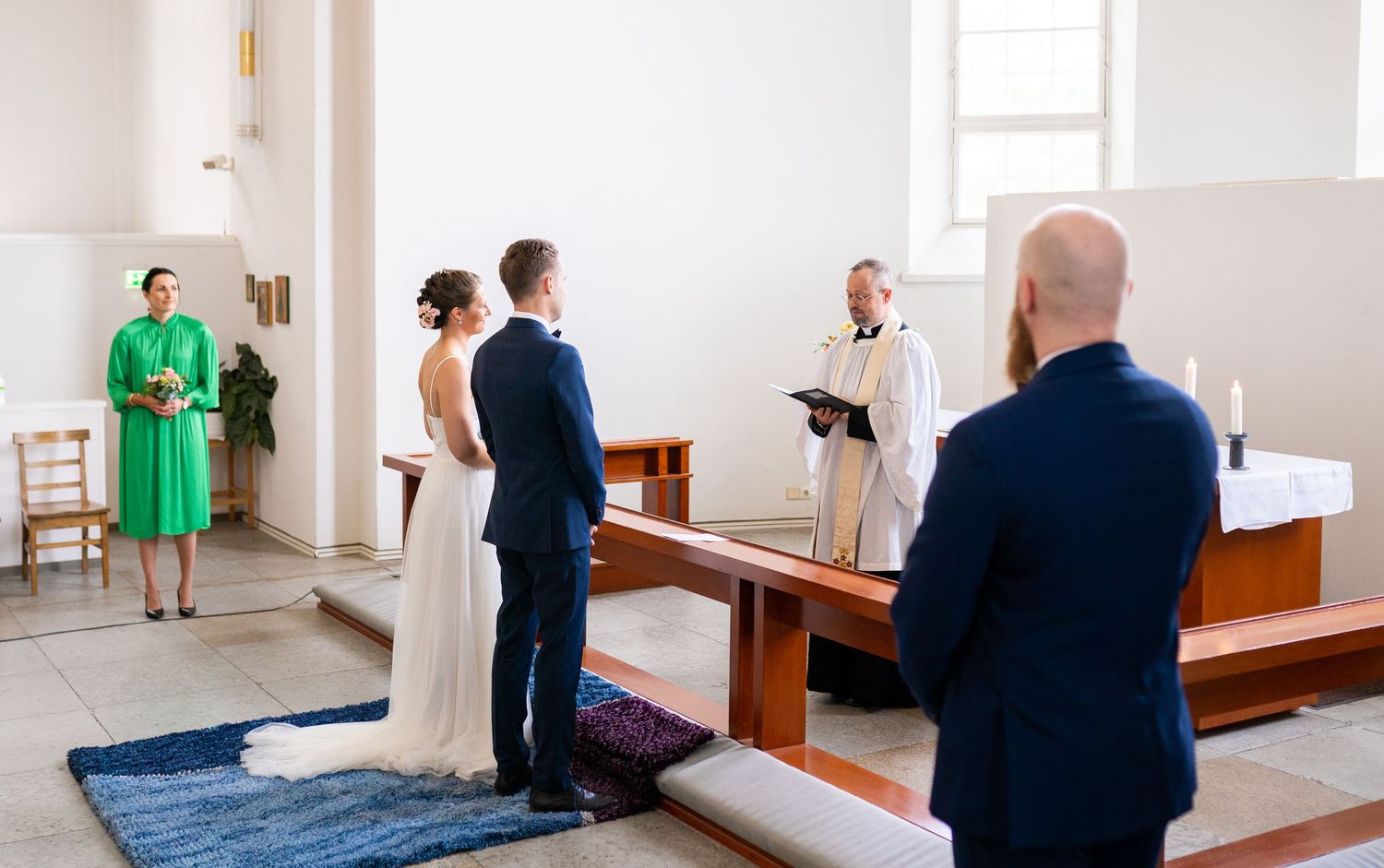 Bride and groom standing before a pastor during an intimate church wedding ceremony.