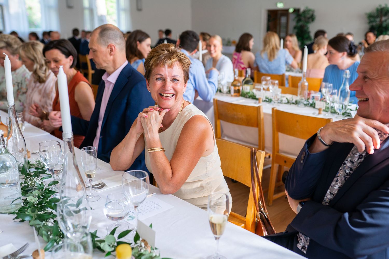 Smiling woman enjoying wedding reception dinner at elegantly decorated table with candles.