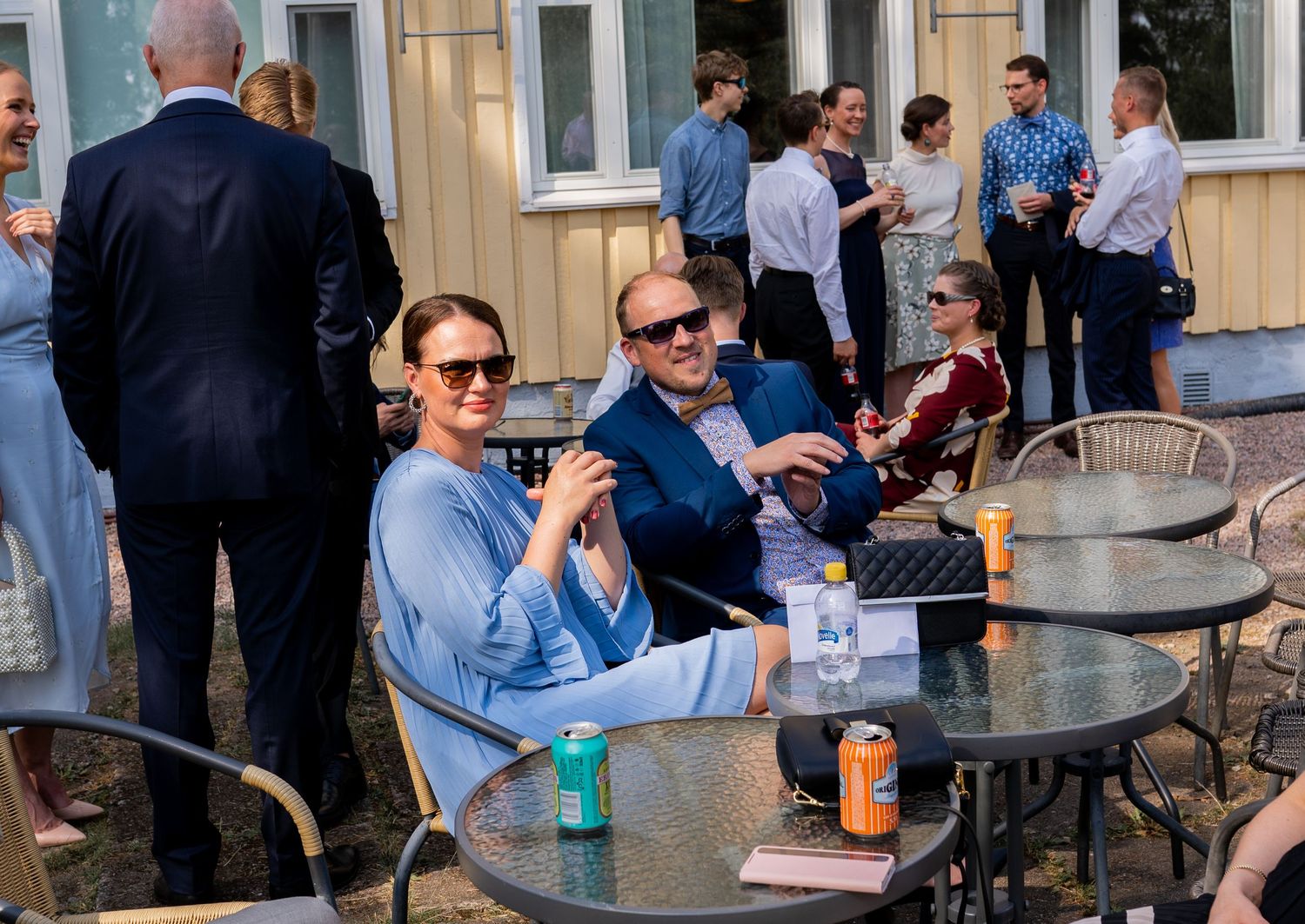 Wedding guests relaxing at outdoor tables on a sunny day during a reception.