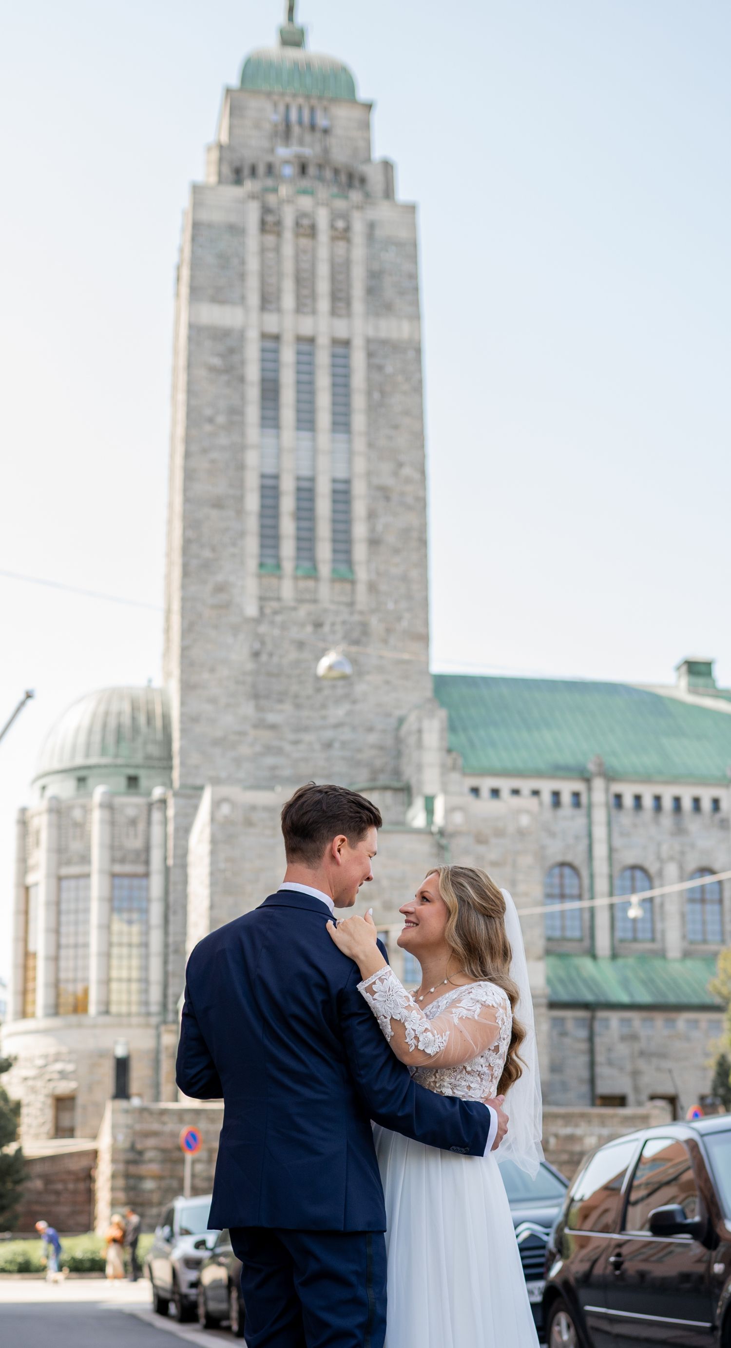Bride and groom embracing in front of Helsinki Central Railway Station on their summer wedding day.