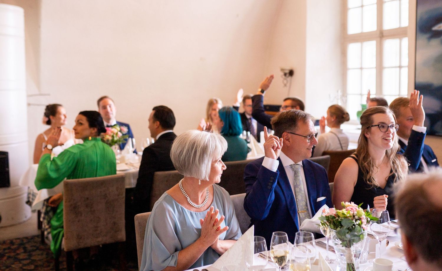 Wedding reception guests applauding and celebrating at beautifully decorated banquet tables.