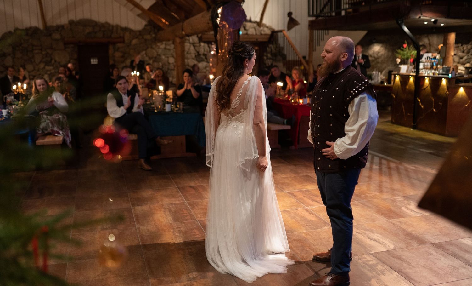 Bride and groom share their first dance in a rustic wedding venue with stone walls and warm candlelit ambiance.