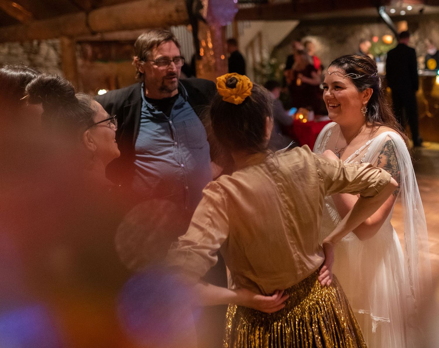 People in elegant costumes socializing at a festive medieval-themed event in a warmly lit venue.