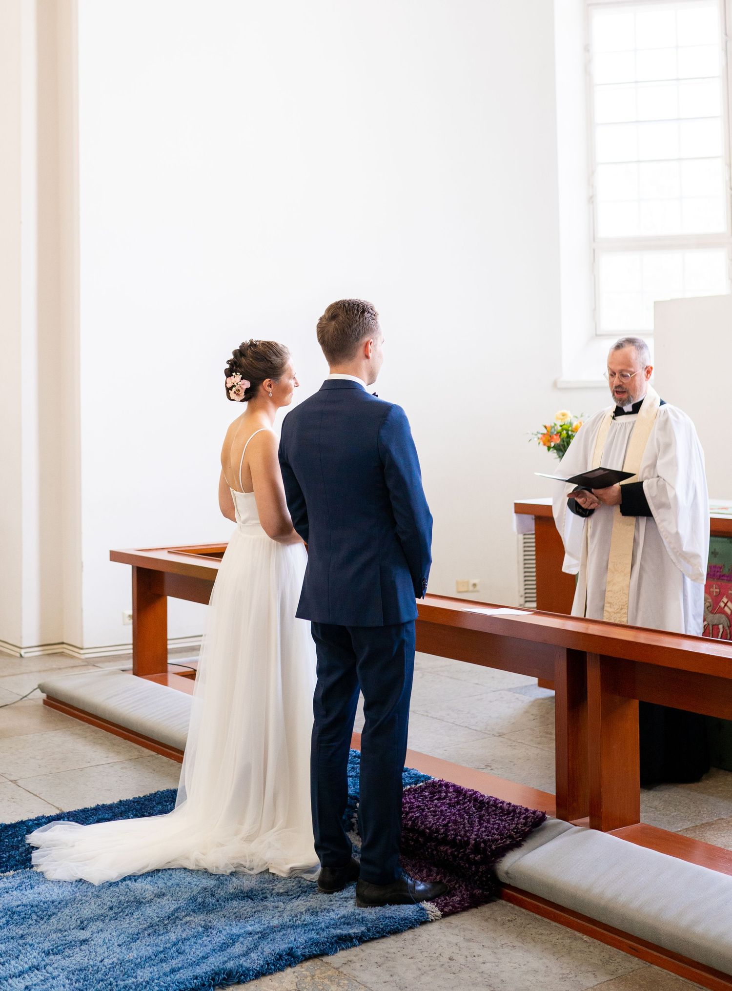 Couple standing before officiant at church altar during wedding ceremony.
