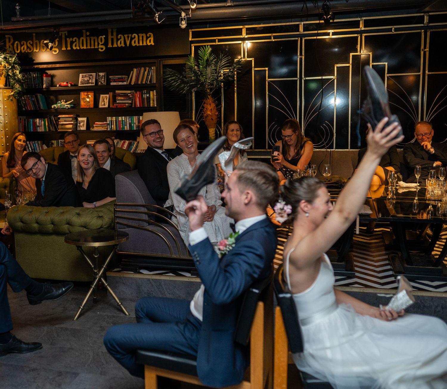 Bride and groom holding up shoes during wedding shoe game at Trading Havana venue.