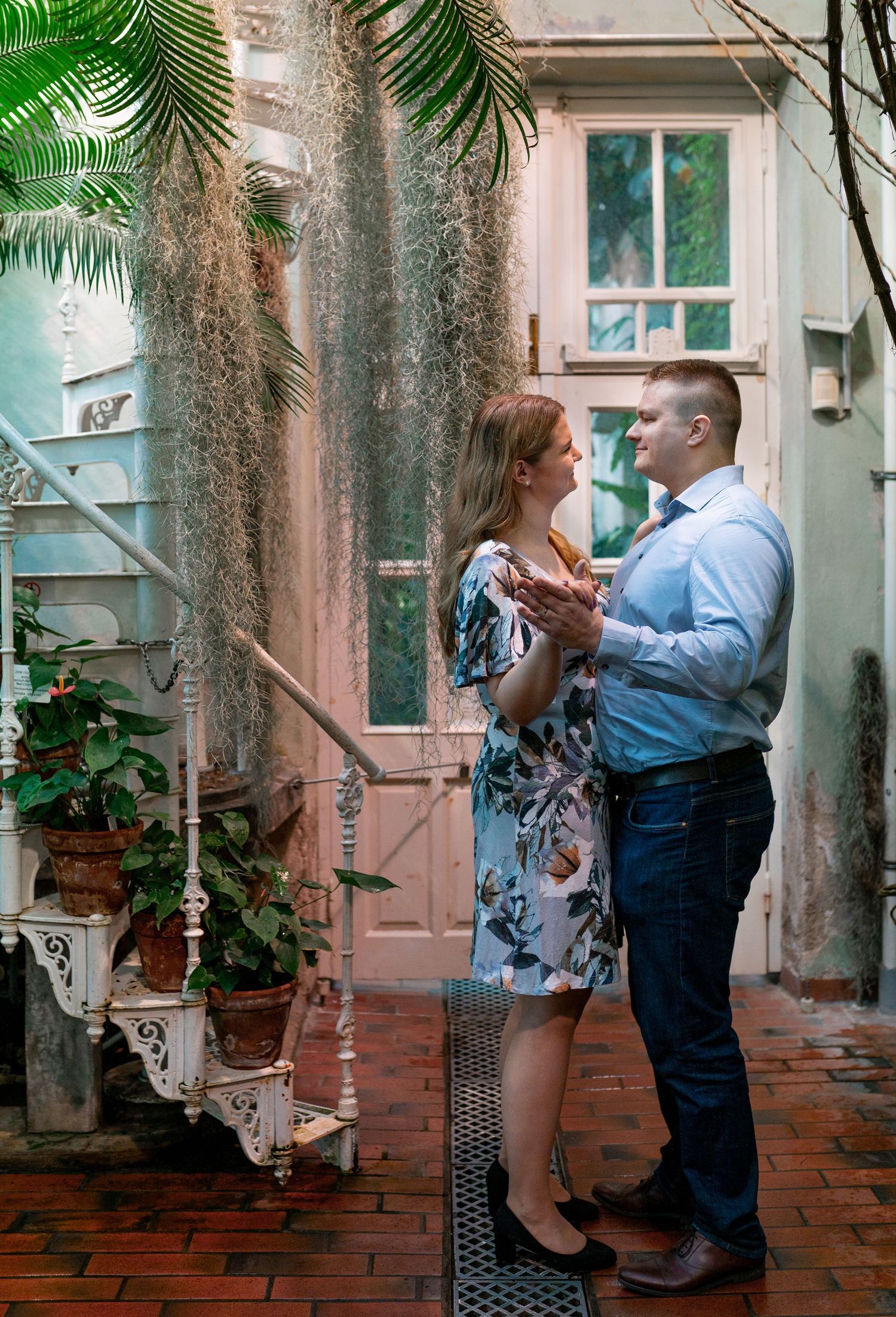 Couple dancing romantically in a lush courtyard with Spanish moss, brick floors, and vintage decor.