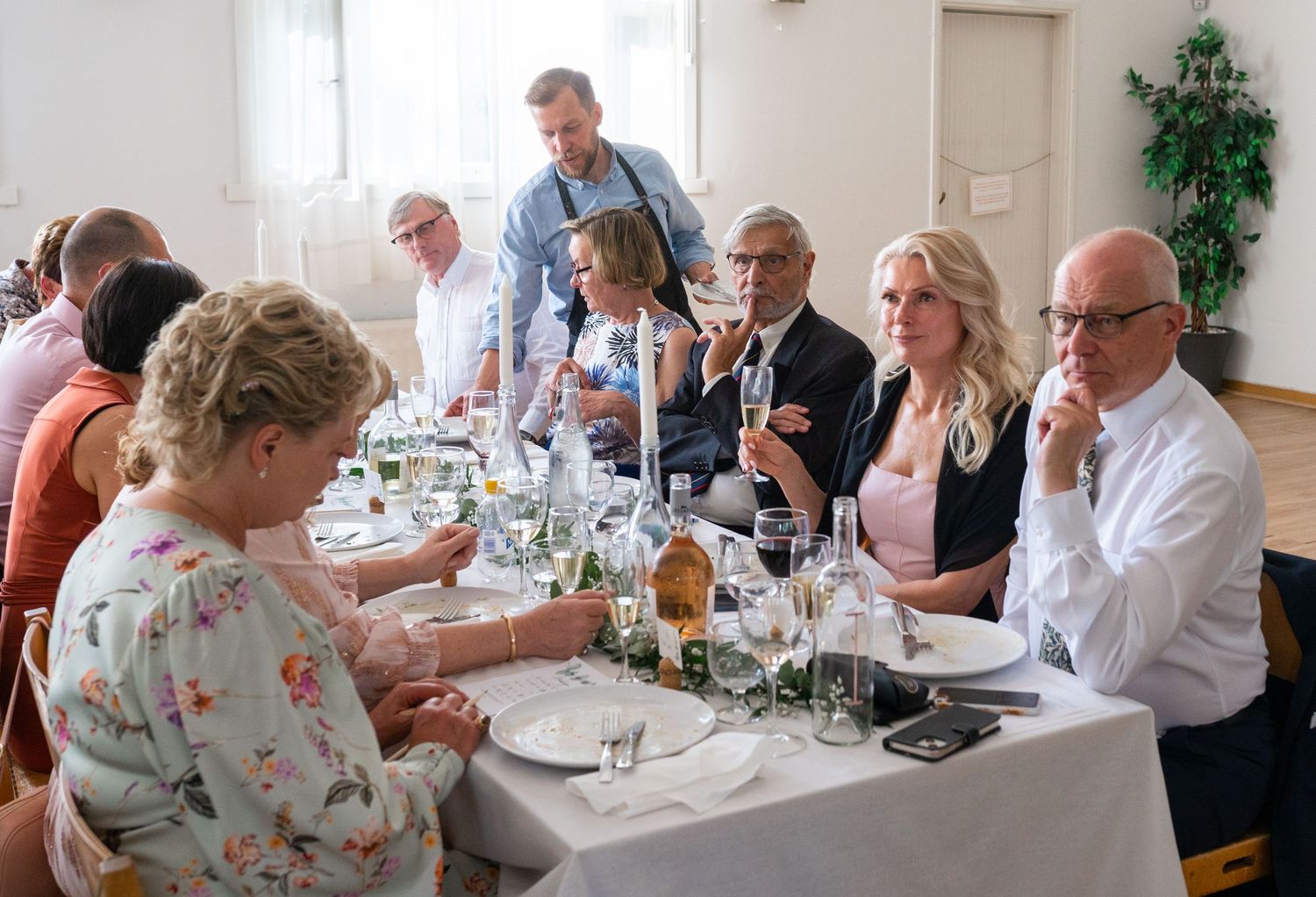 Wedding guests enjoying champagne and conversation at a beautifully set reception dinner table.