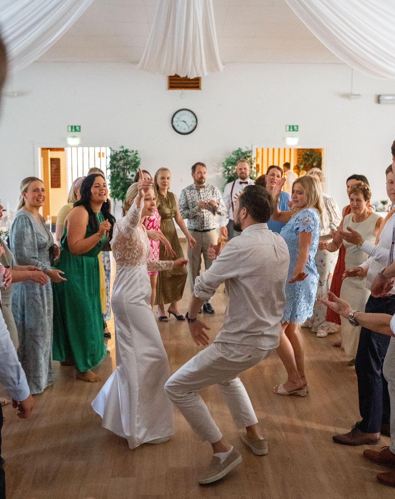 Bride and groom share an energetic first dance surrounded by cheering guests at their wedding reception.