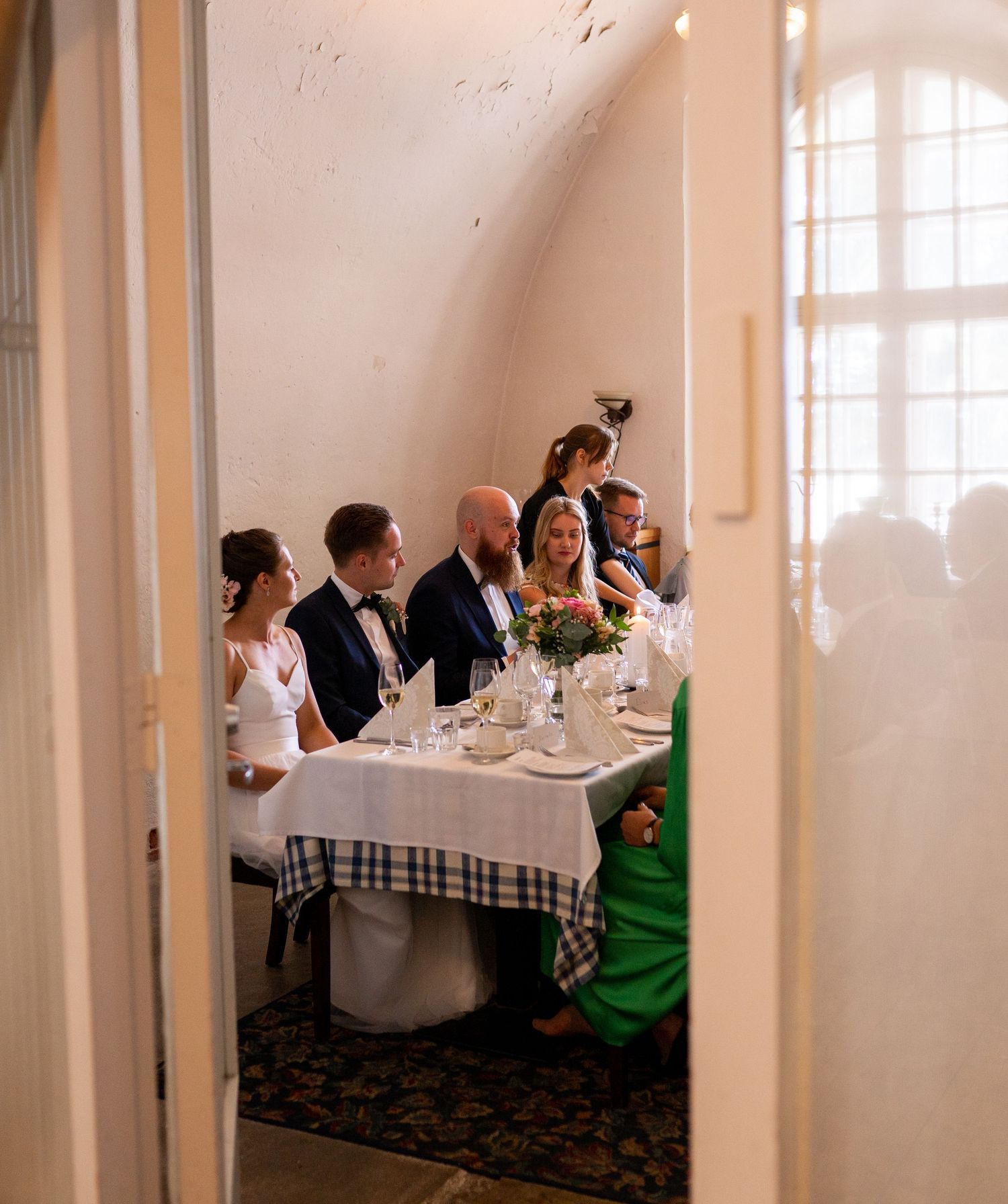 Wedding guests seated at a decorated table in an elegant vaulted room during a reception dinner.