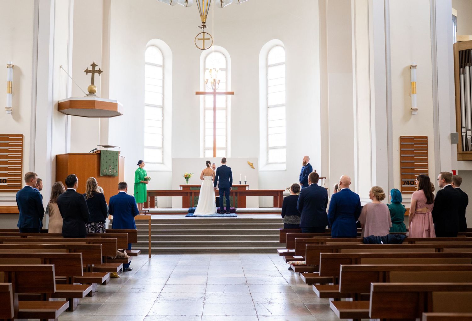 Wide view of a church wedding ceremony with guests seated in pews facing the altar.