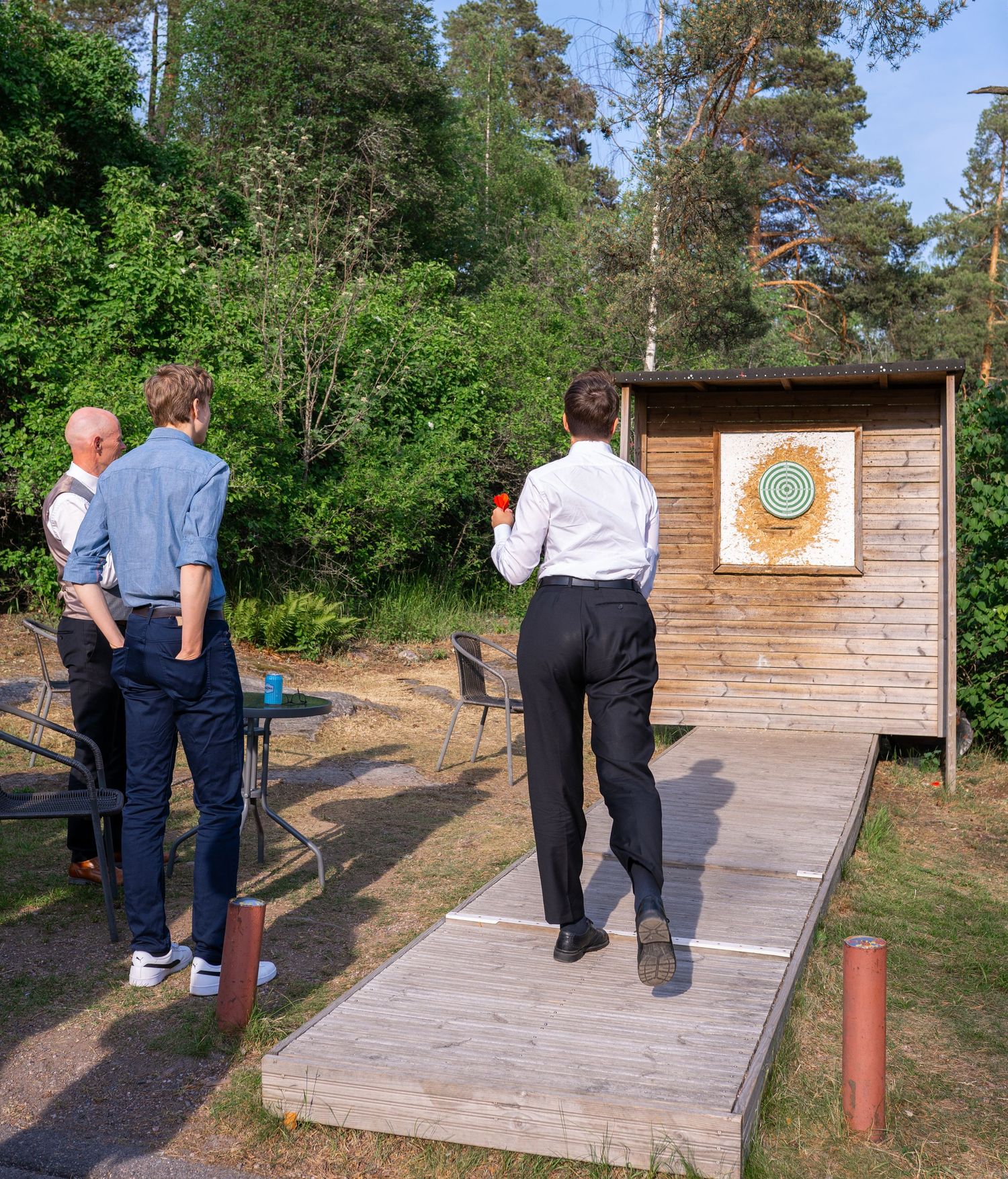 Wedding guests playing axe throwing at an outdoor activity station during the reception.