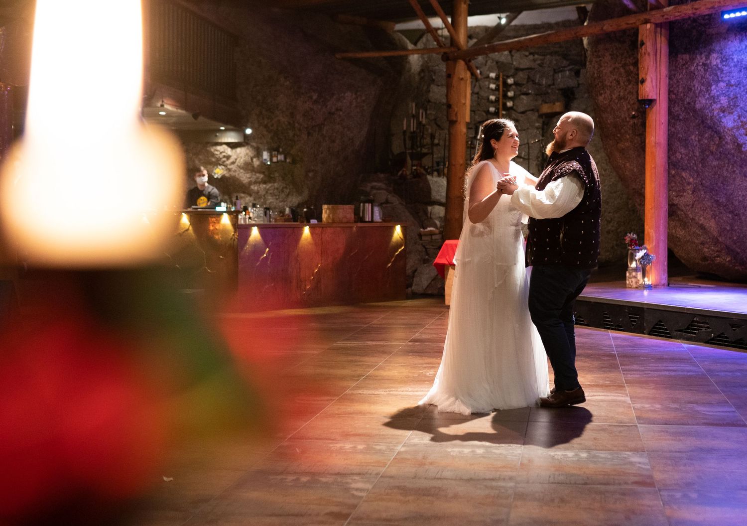 Bride and groom share their first dance in a romantic candlelit rustic barn venue during their wedding reception.