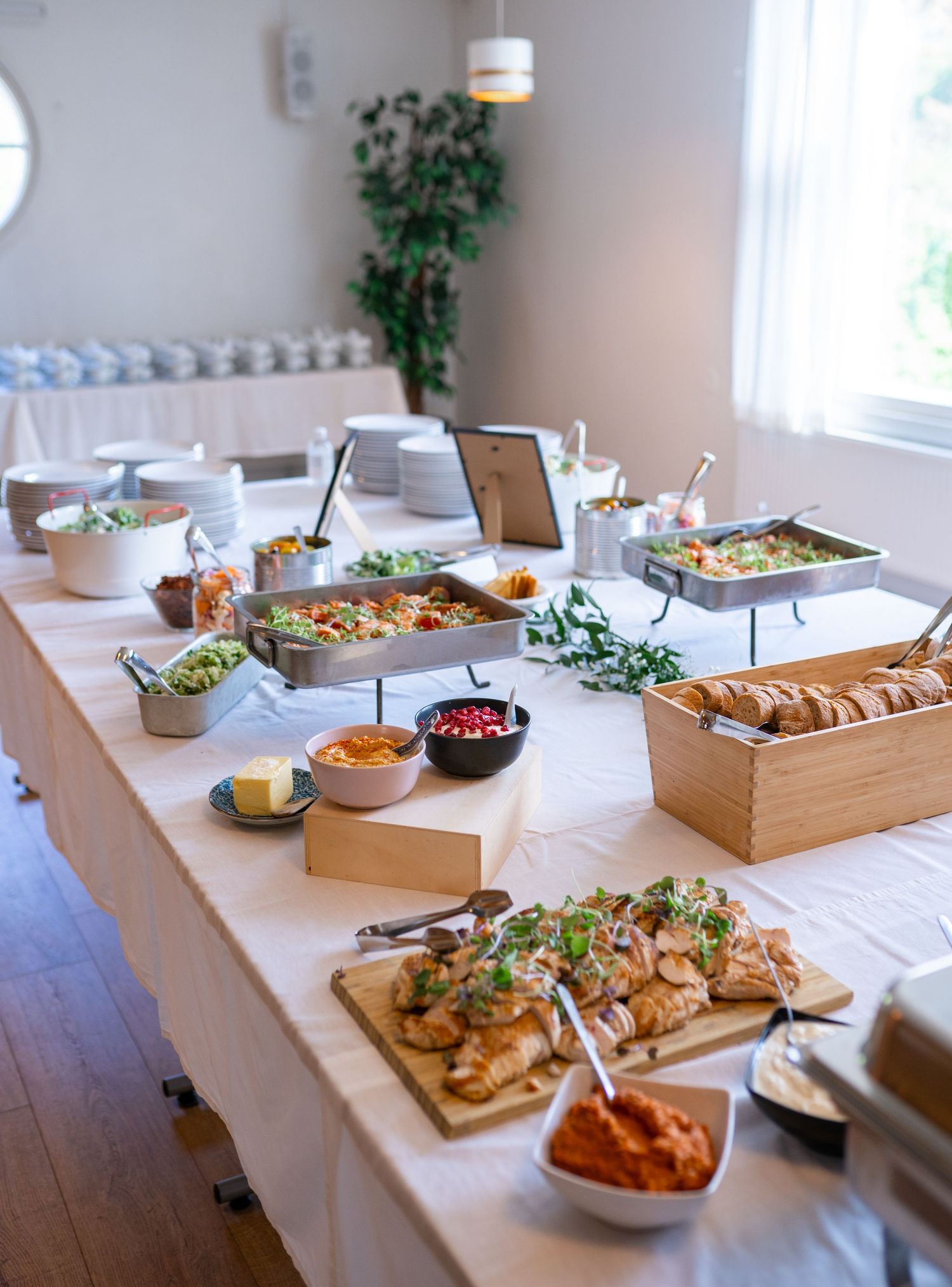 Beautifully arranged wedding reception buffet with croissants, salads, and warm dishes on white linen.