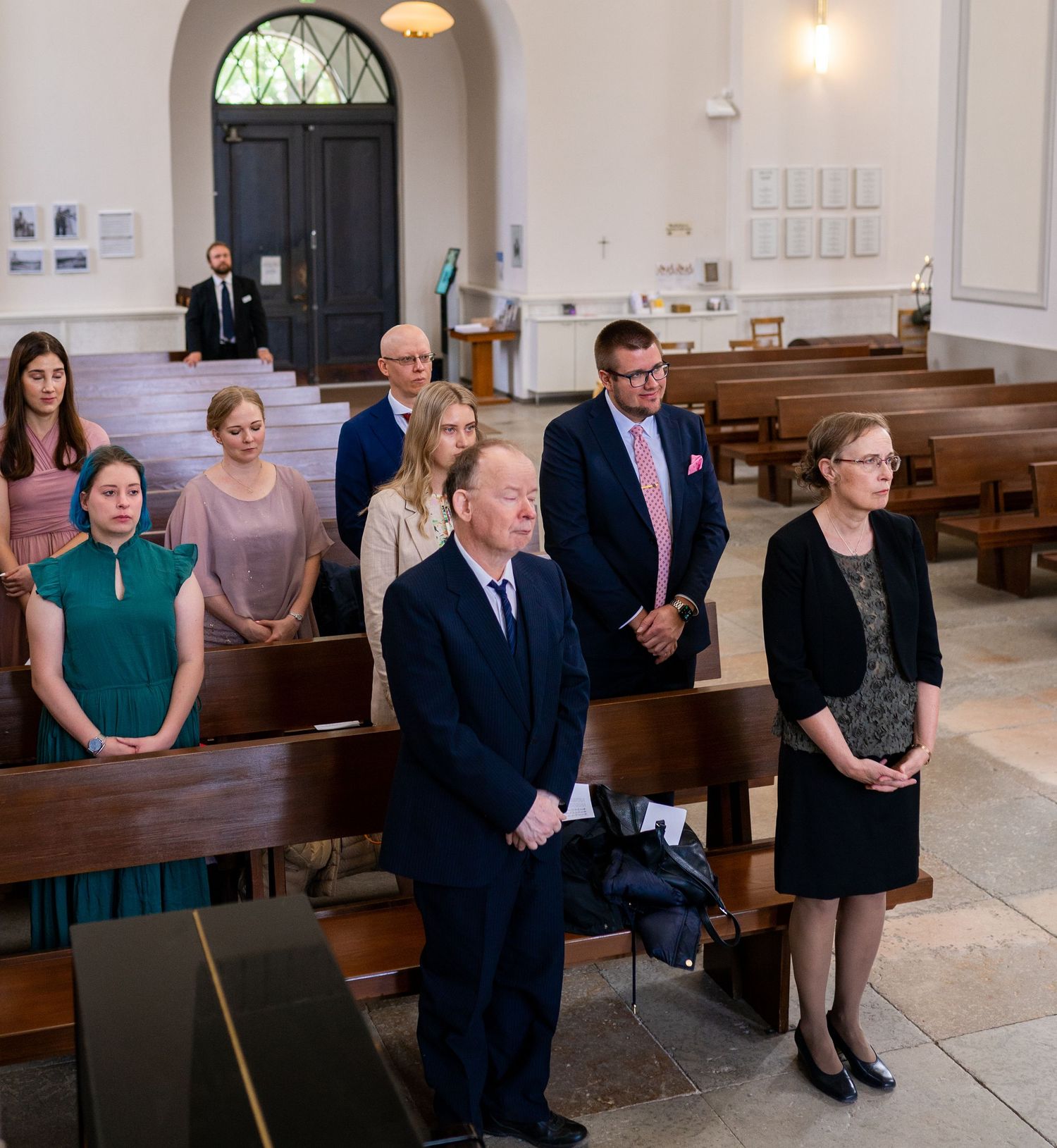Wedding guests standing in church pews during ceremony.