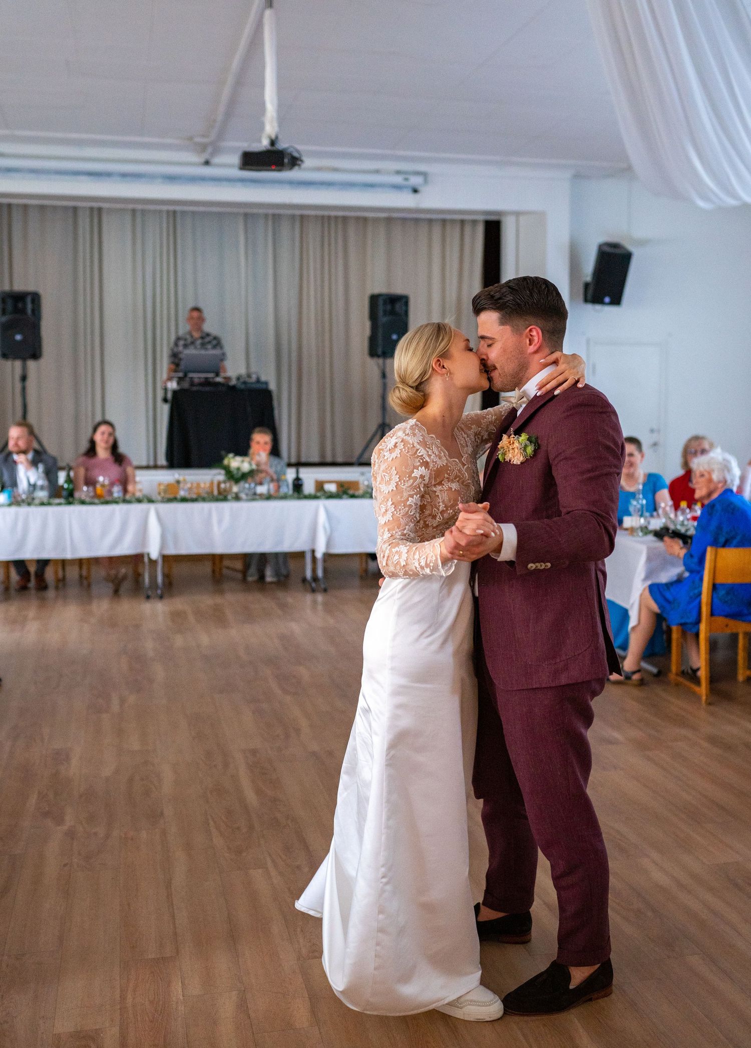 Bride and groom share a tender kiss during first dance at elegant wedding reception venue.