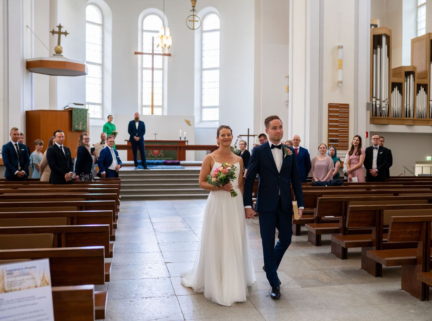 Newlyweds walking hand in hand down church aisle after wedding ceremony.